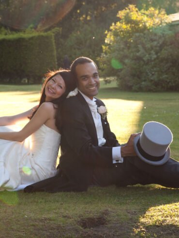 bride and groom sit on the ground back to back at their Alice in Wonderland wedding