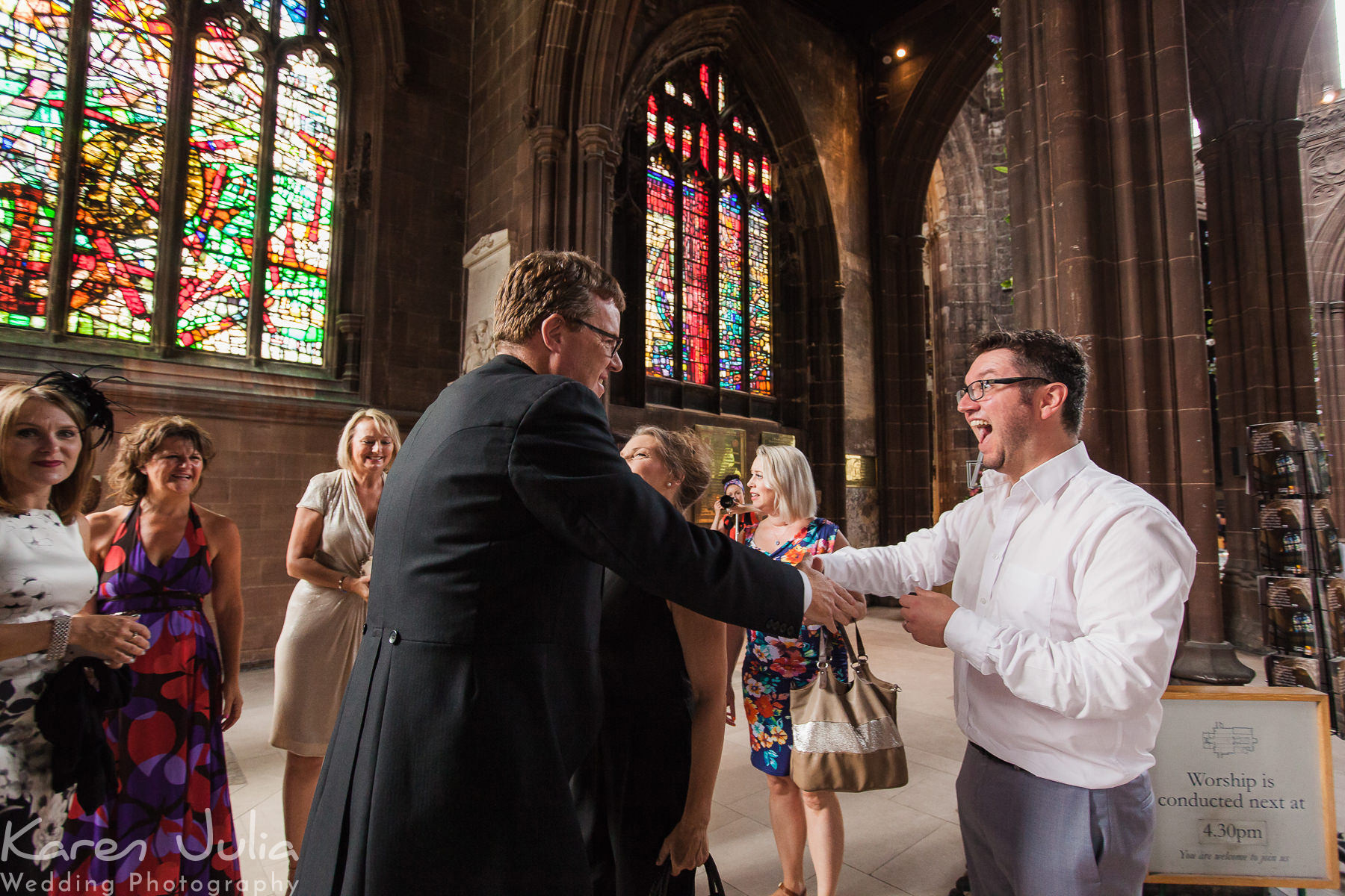 groom greets guests as they arrive for Manchester Cathedral wedding