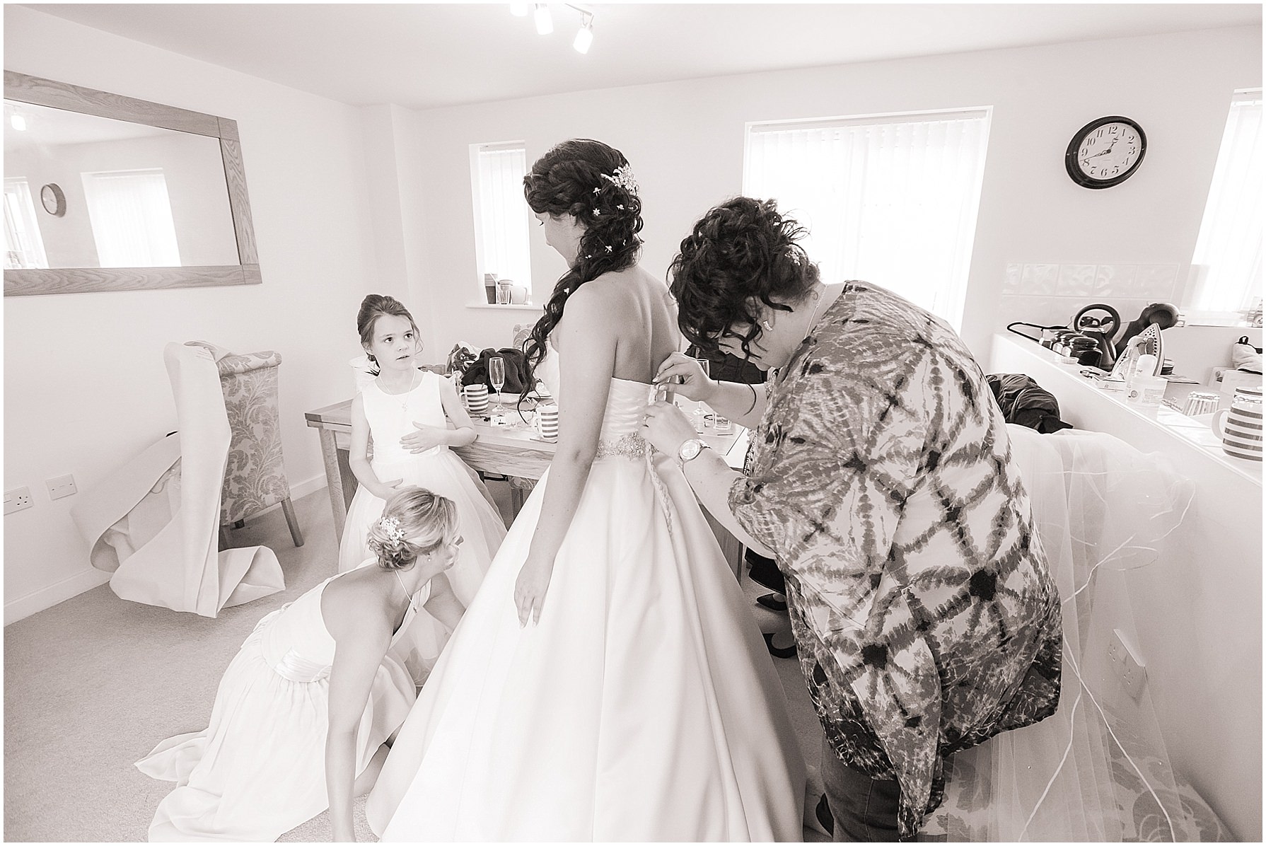 bride is helped in to dress by bridesmaids