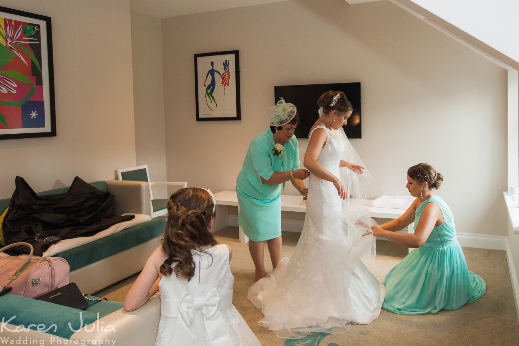 bridesmaids helping bride in to her dress
