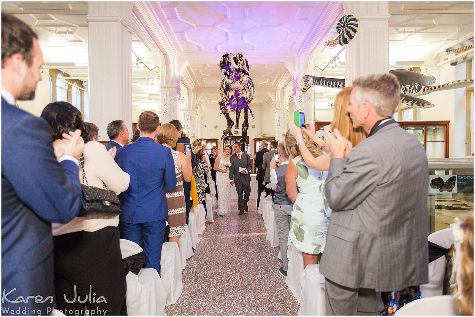 bride and groom walk up aisle together in Manchester Museum