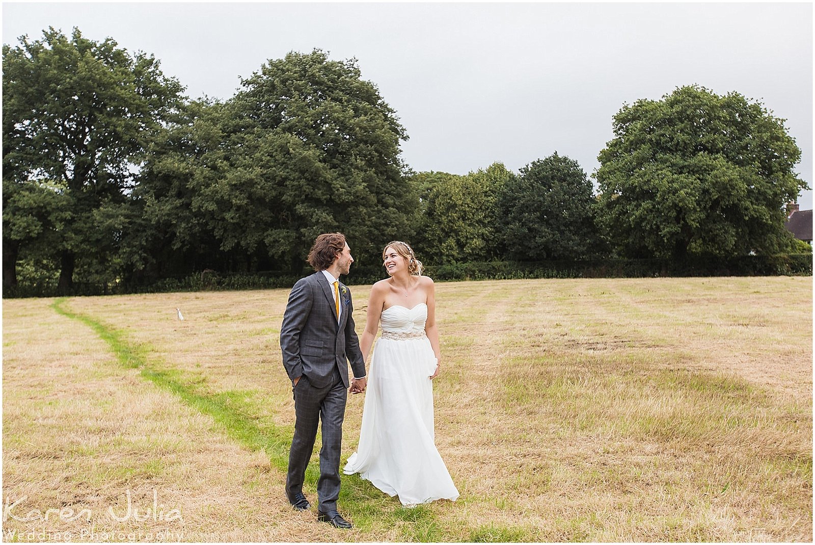 bride and groom walk in the field next to Victory Hall in Mobberly