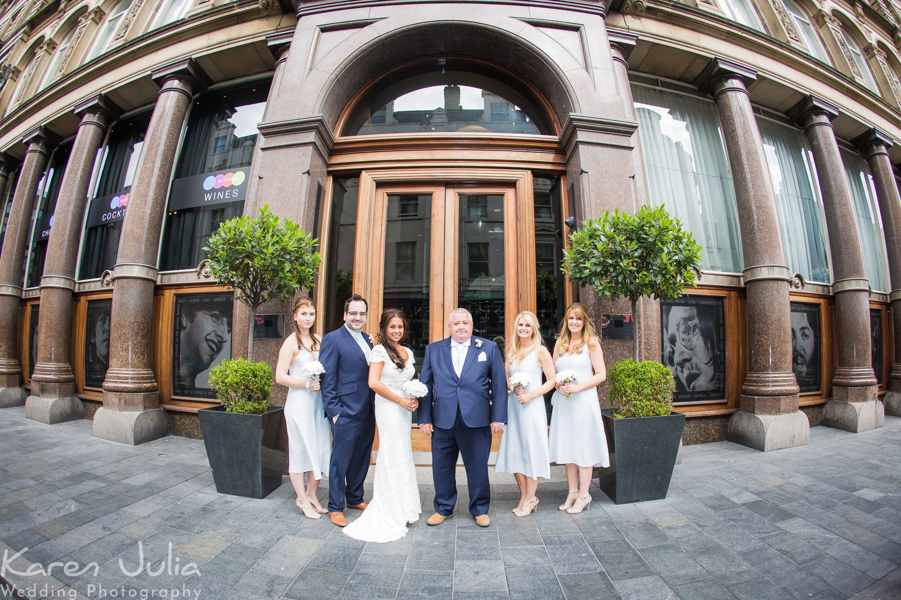 a wedding group photo outside the entrance of the Hard Days Night hotel