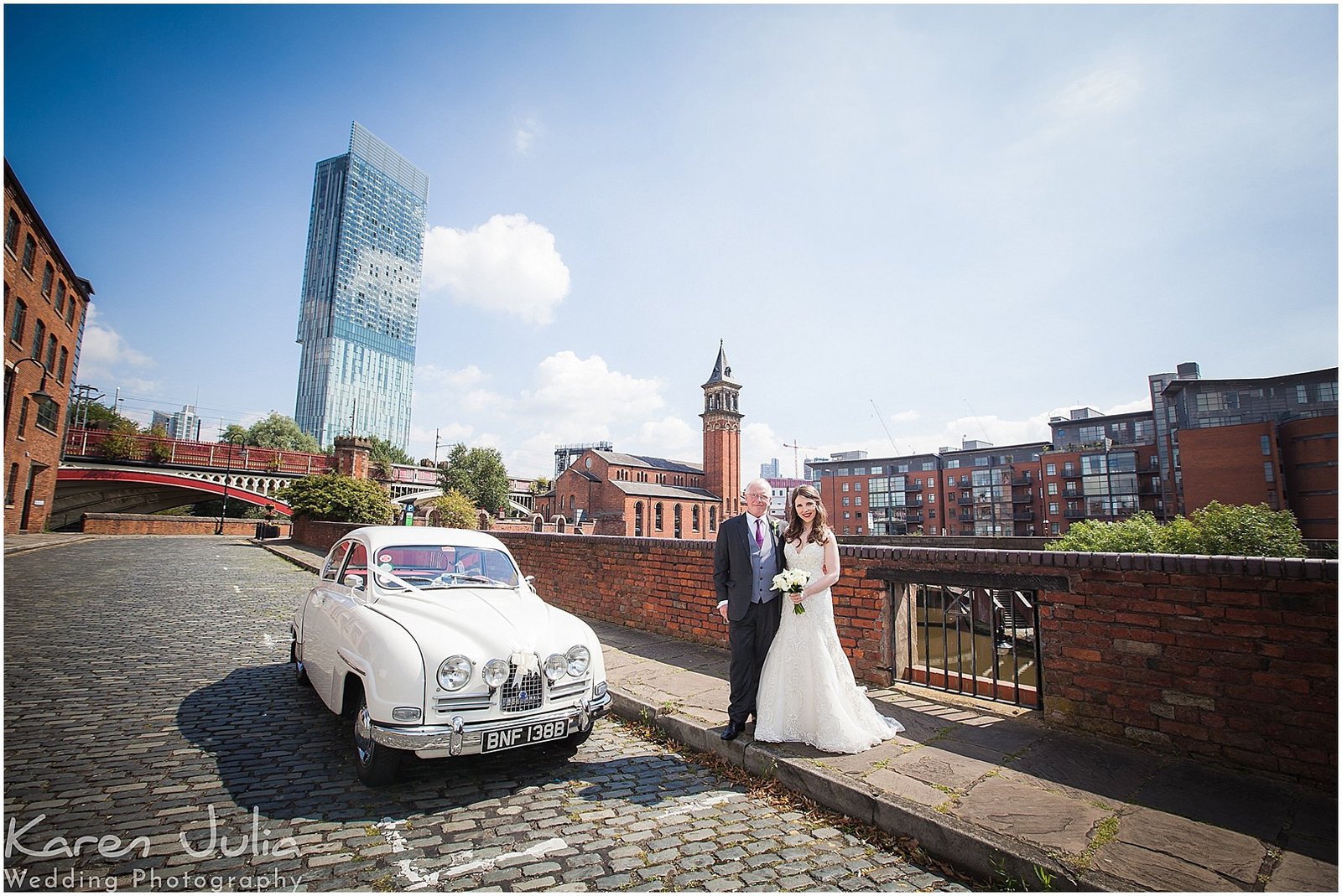 bride and dad pose with vintage SAAB wedding car in Castlefield Manchester