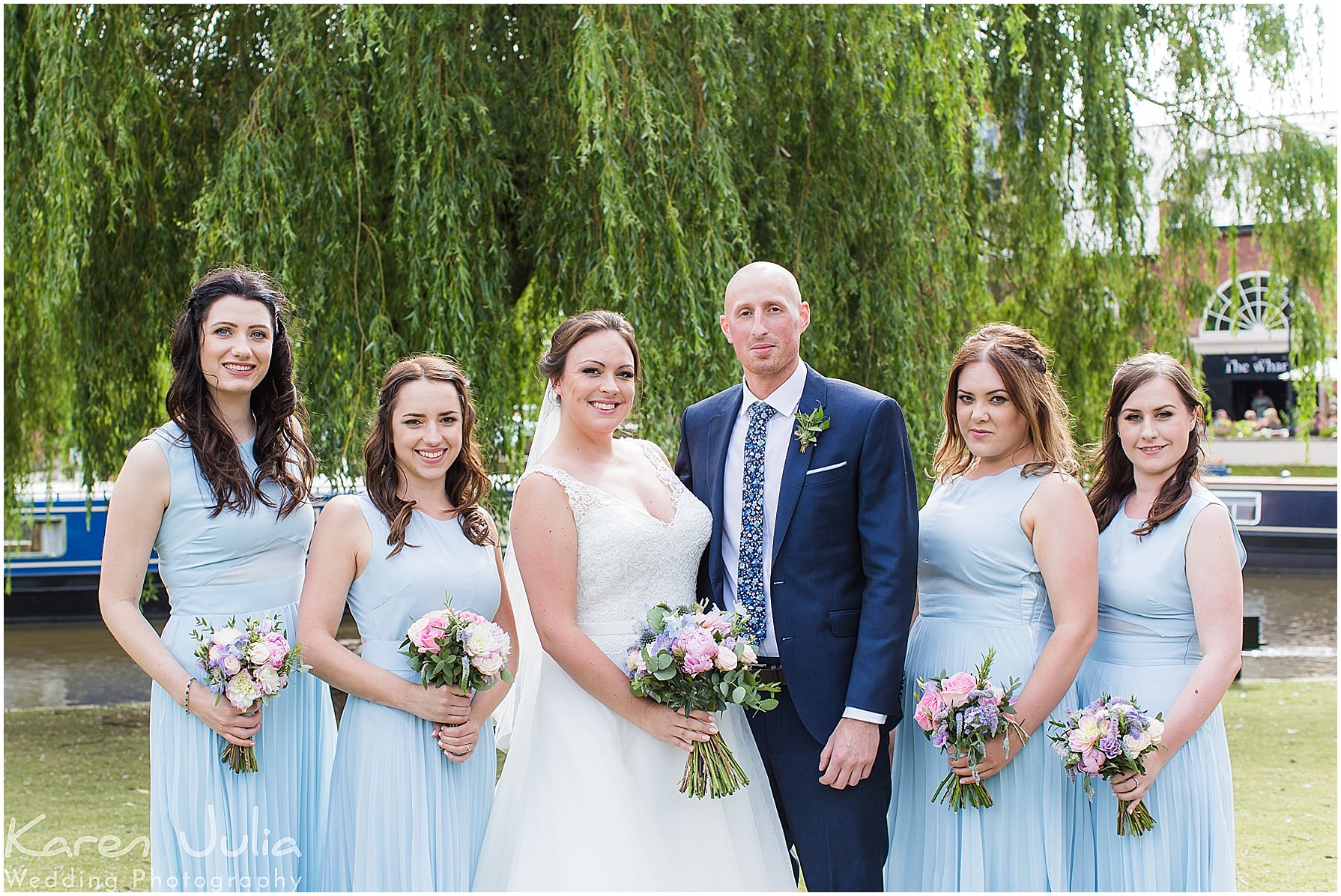 bride and groom with bridesmaids wearing pastel blue dresses near Castlefield Rooms