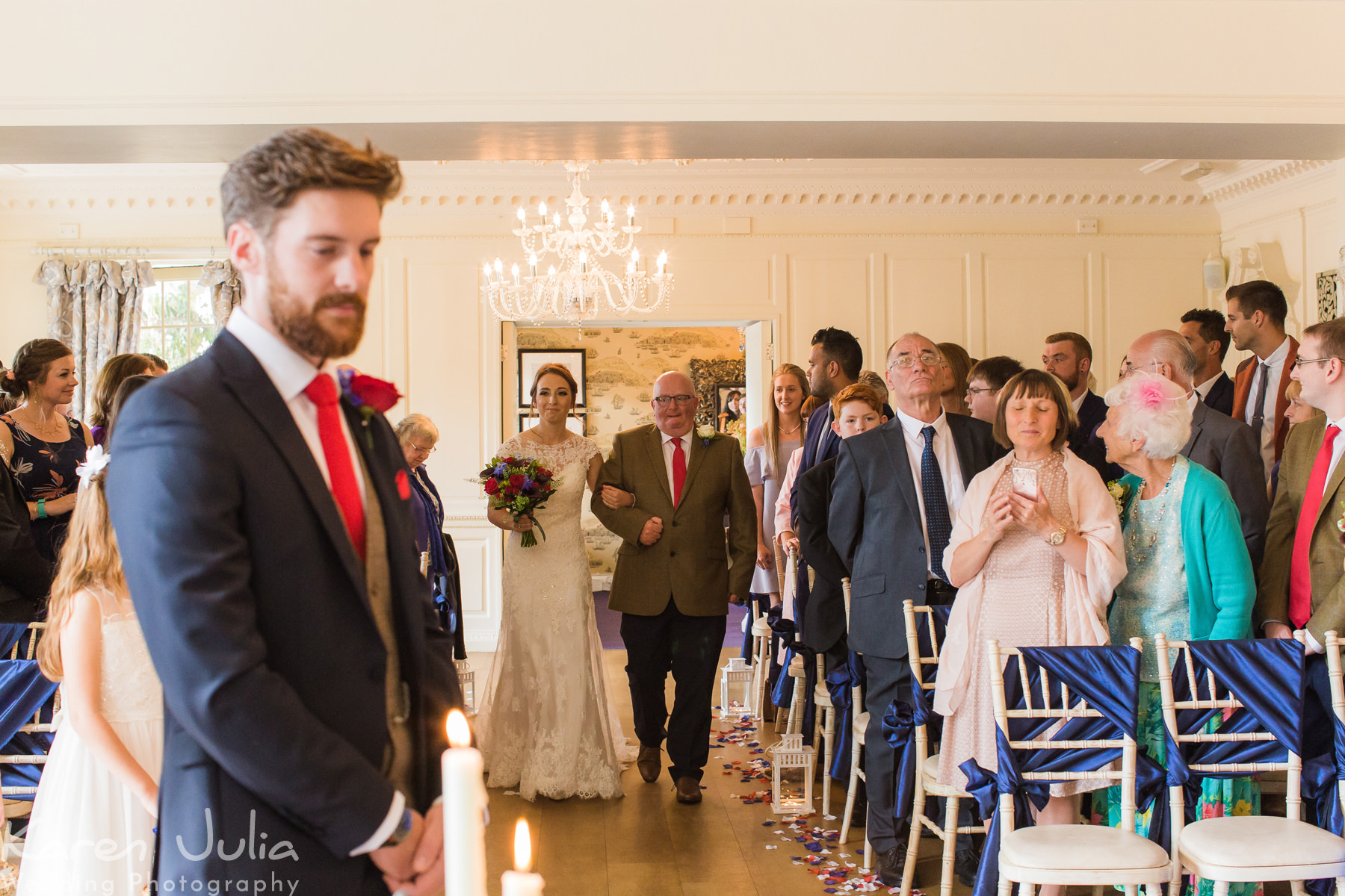 bride walks down aisle to meet groom at Eaves Hall