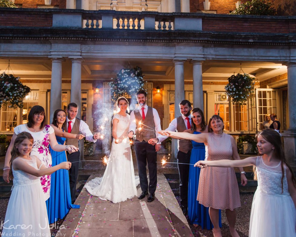 bridal party with sparklers at dusk outside Eaves Hall