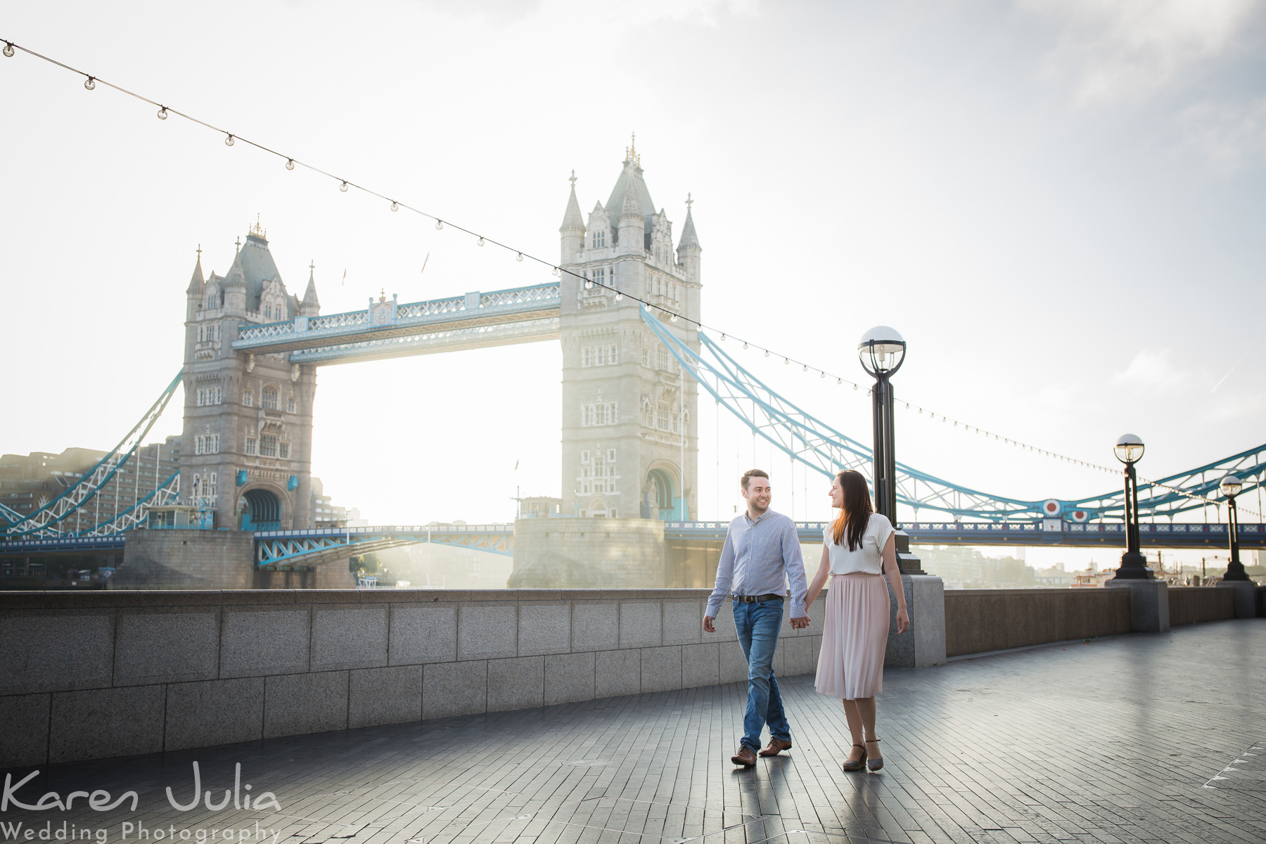 couple walking along with Tower Bridge in the background, by Karen Julia Photography