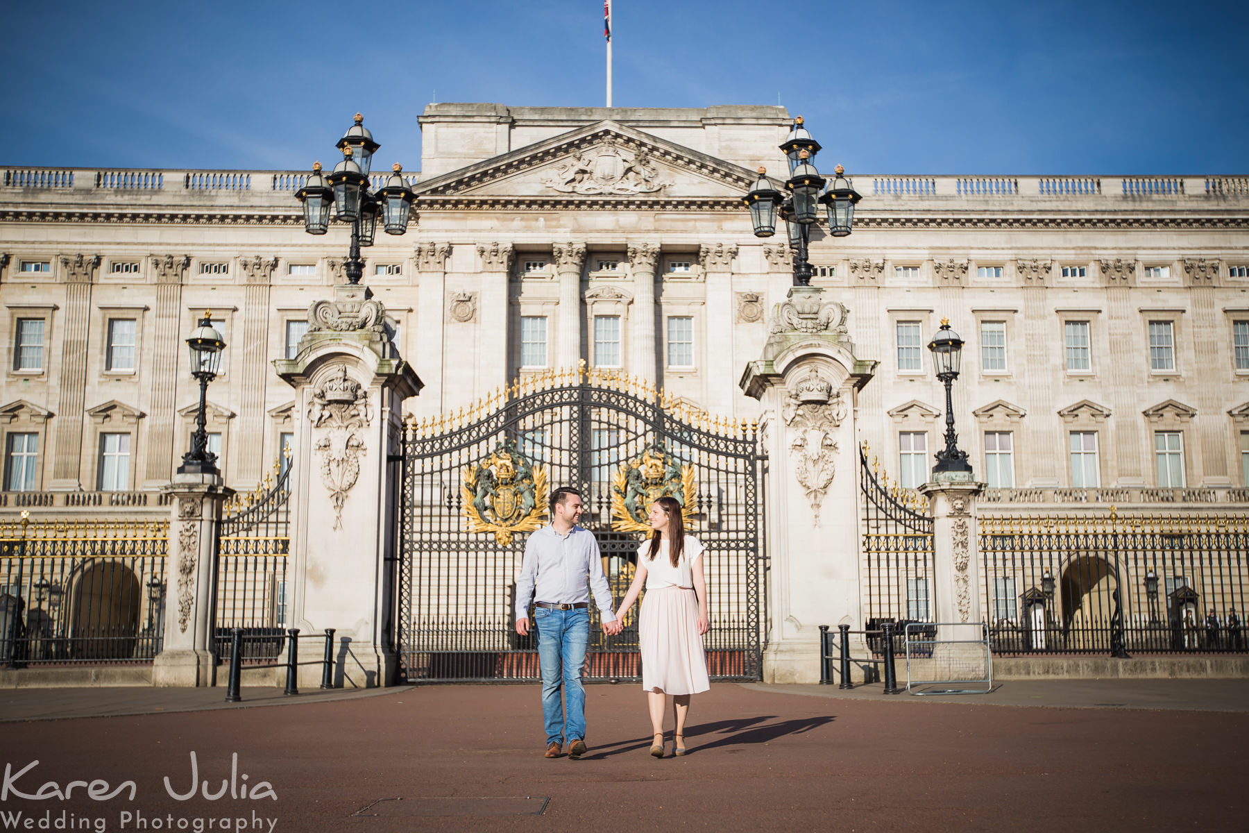 couple walk away from Buckingham Palace during their London pre-wedding photography