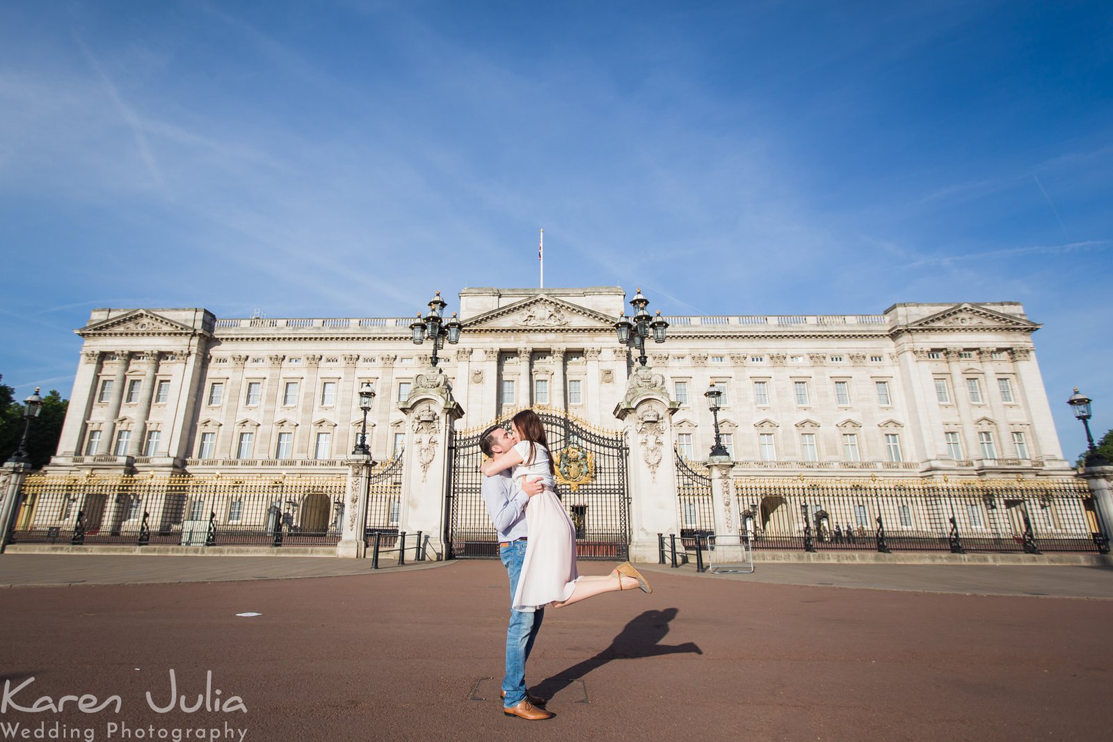 couple embrace during engagement portrait shoot in front of Buckingham Palance