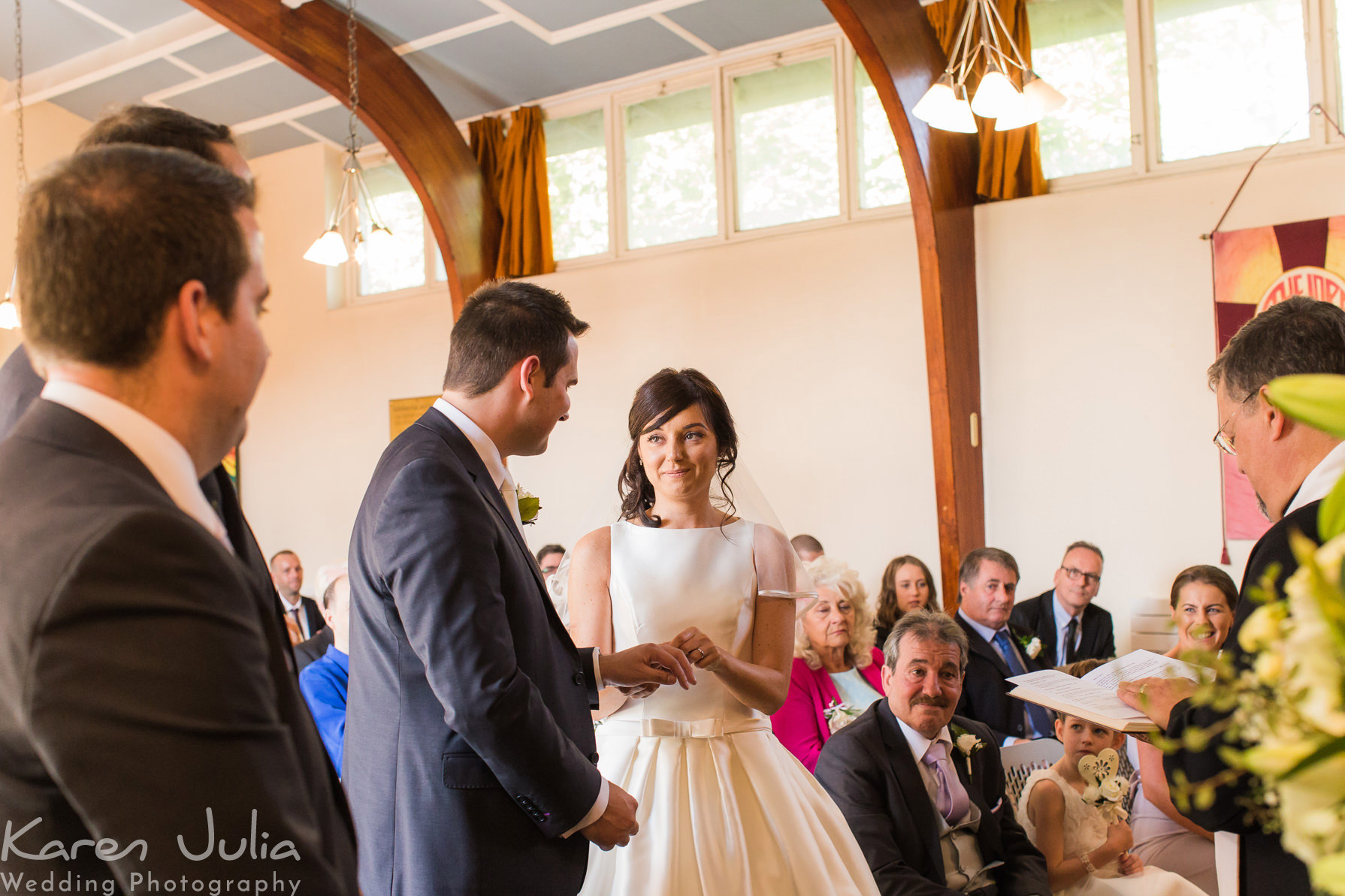 bride and groom exchange rings at their wedding ceremony at Cornerstone Methodist church