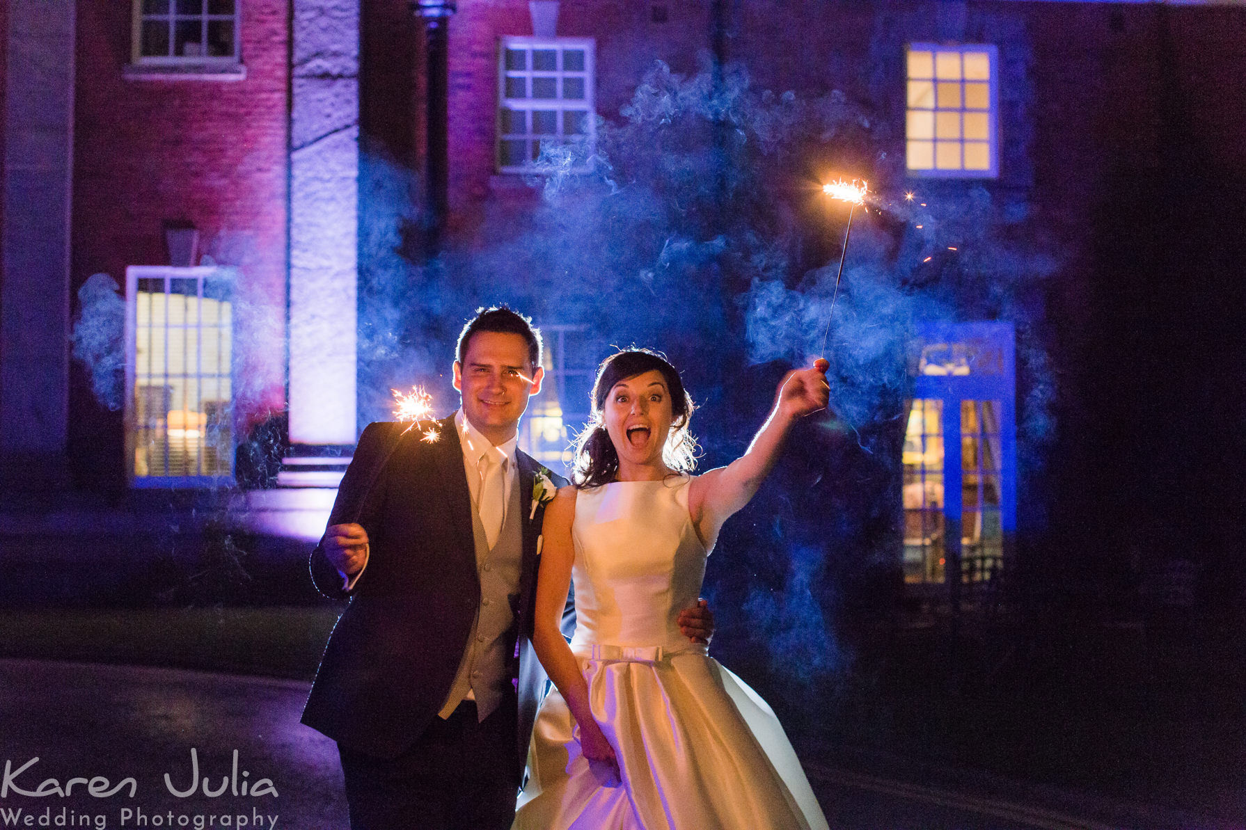 bride and groom holding sparklers for a photo at their autumn wedding