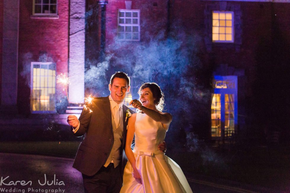 bride and groom holding sparklers for a photo at their autumn wedding