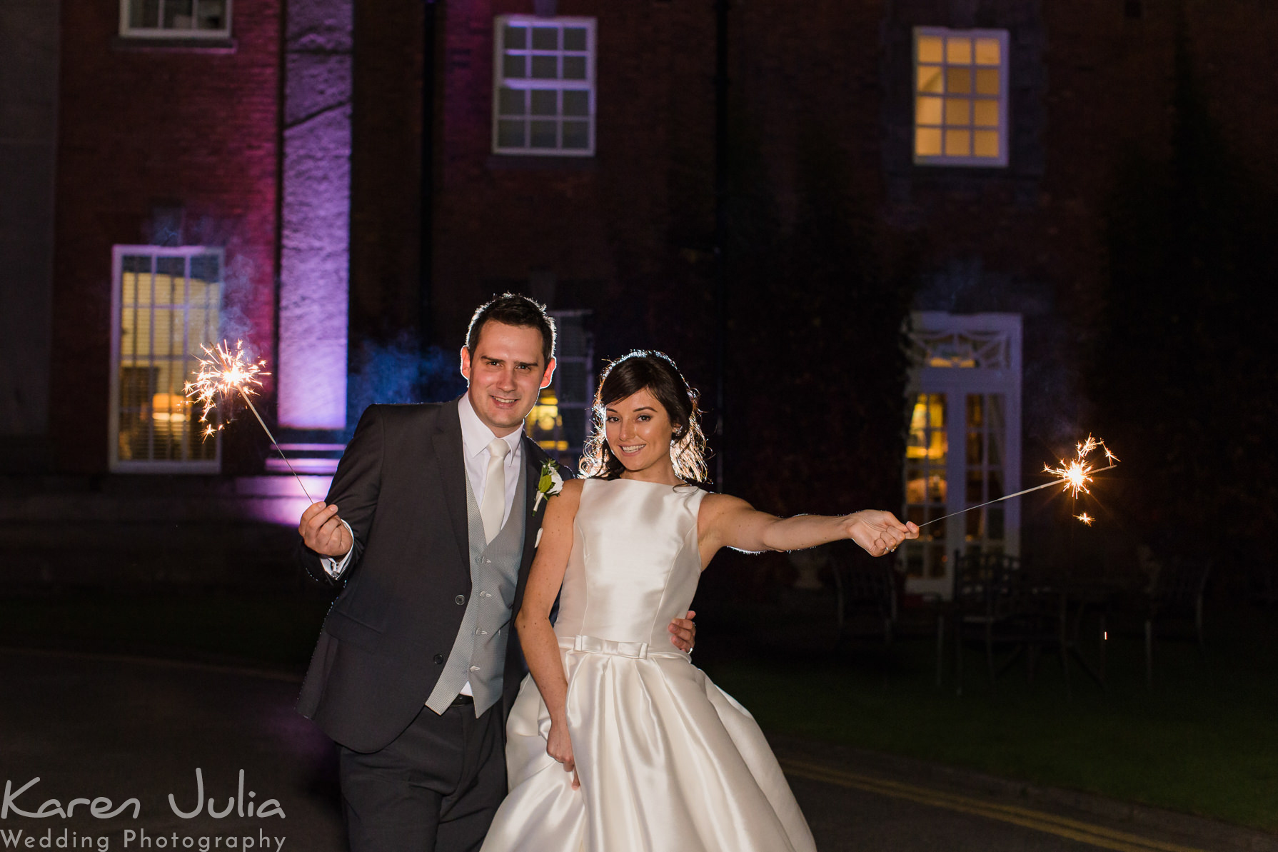 bride and groom pose for a portrait with sparklers outside Mottram Hall