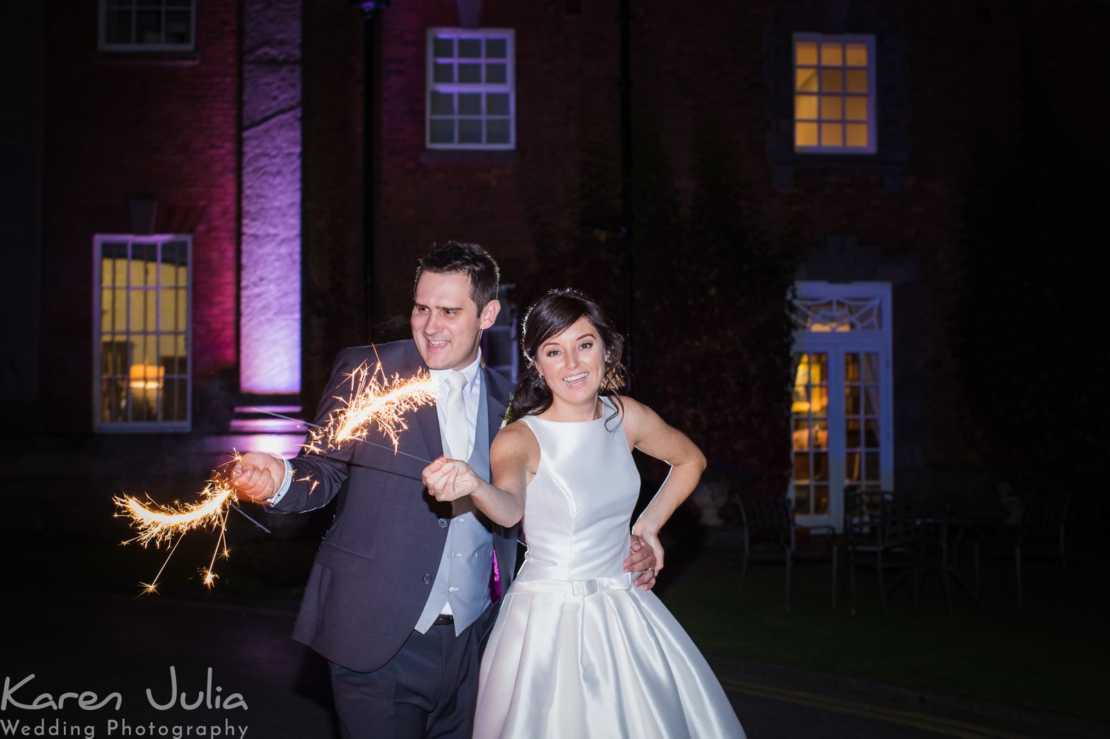 bride and groom play with sparklers at their winter wedding outside Mottram Hall