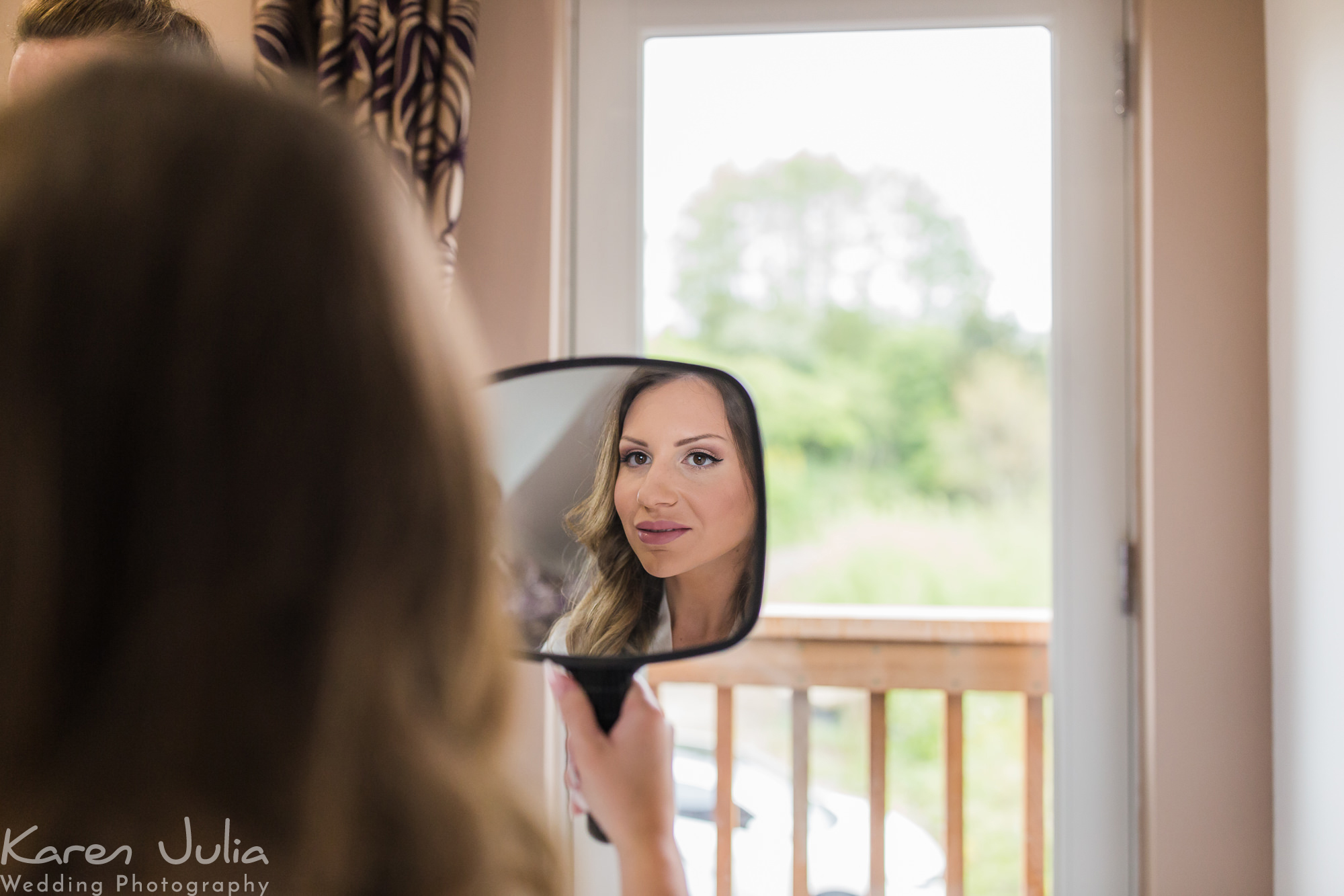bride checks out makeup in mirror during bridal preparations
