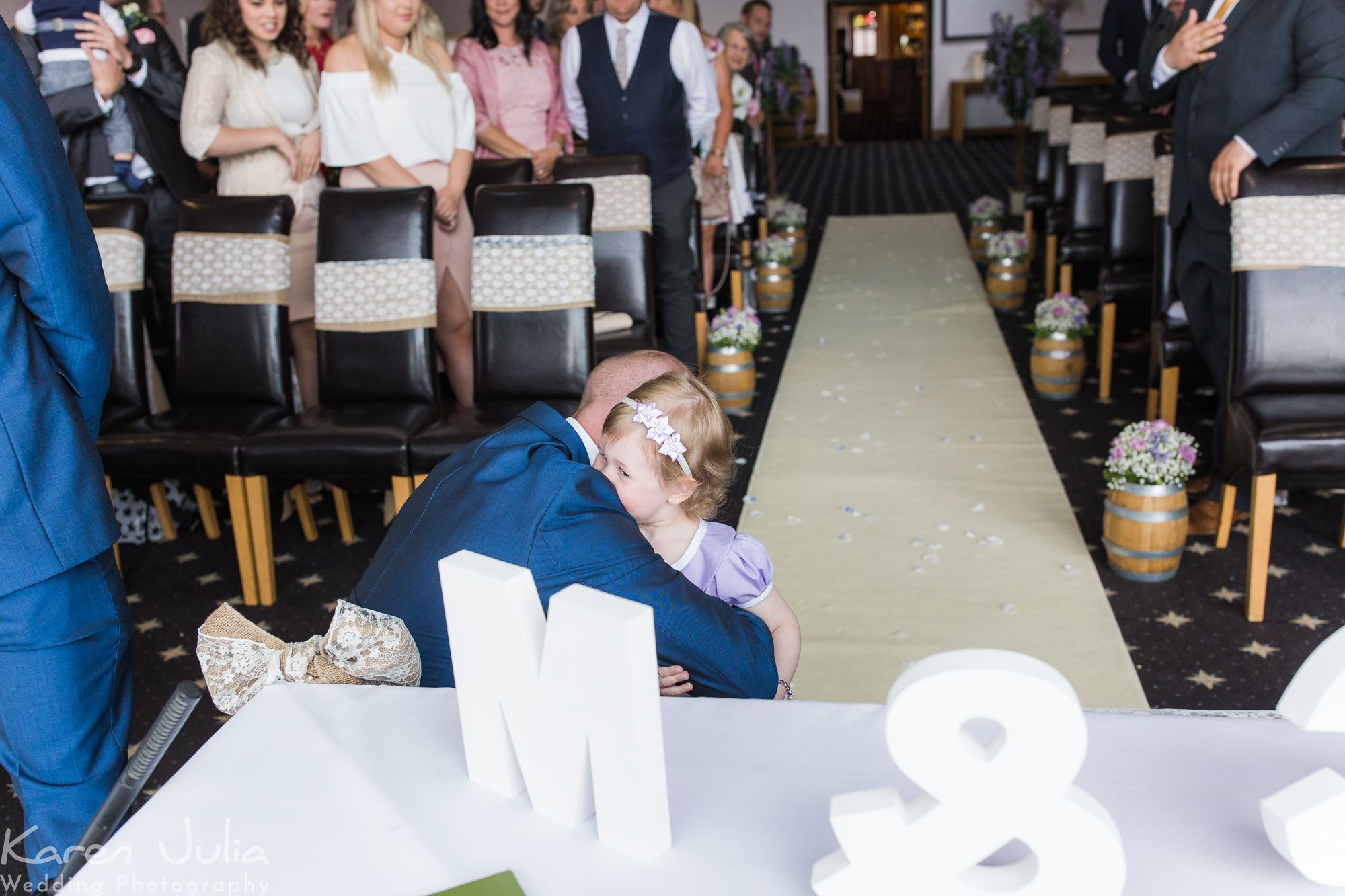 groom hugs daughter, who's a flower girl, just before the wedding ceremony