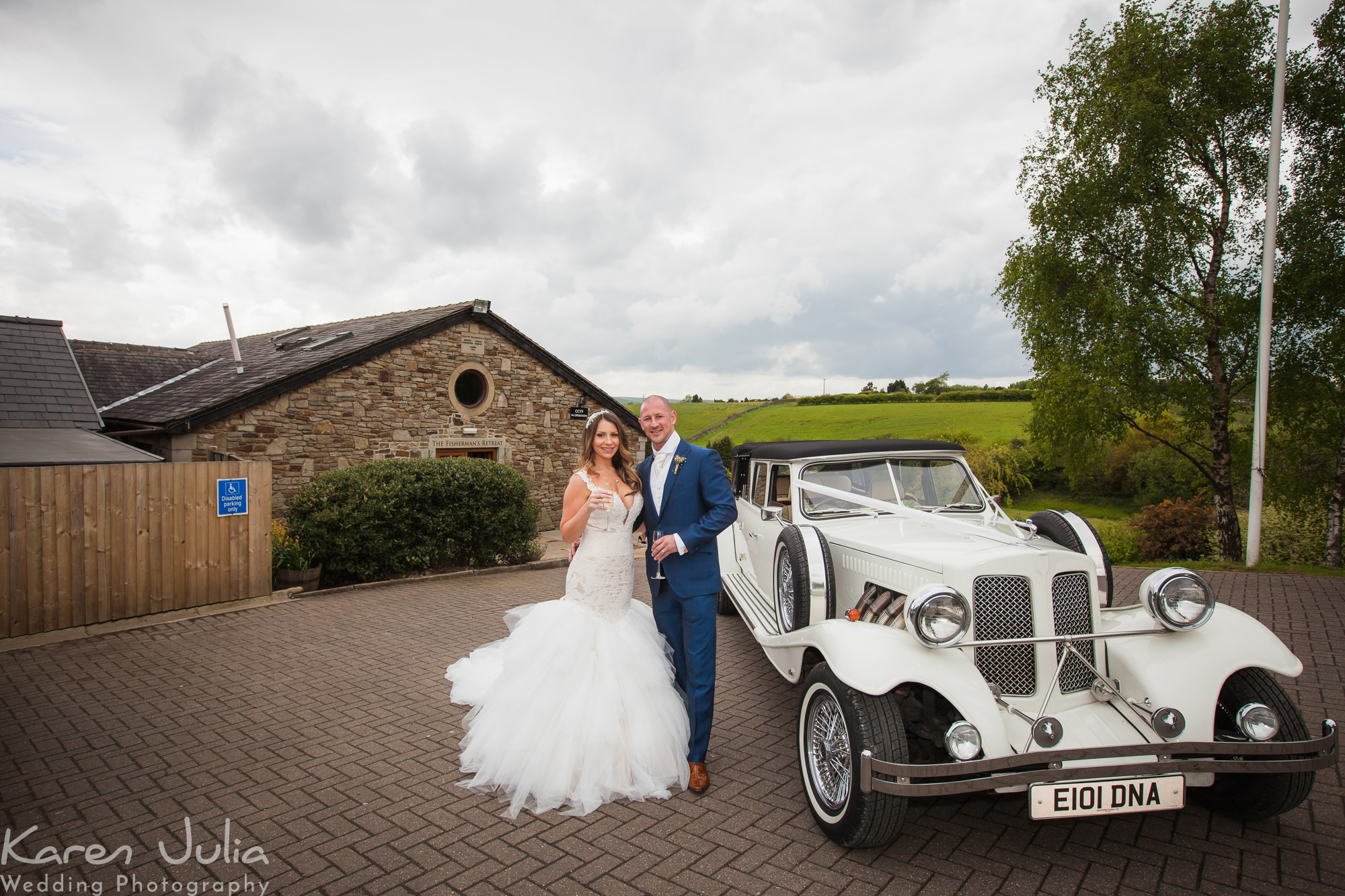 bride and groom pose next to classic wedding car at the Fisherman's Retreat, Ramsbottom