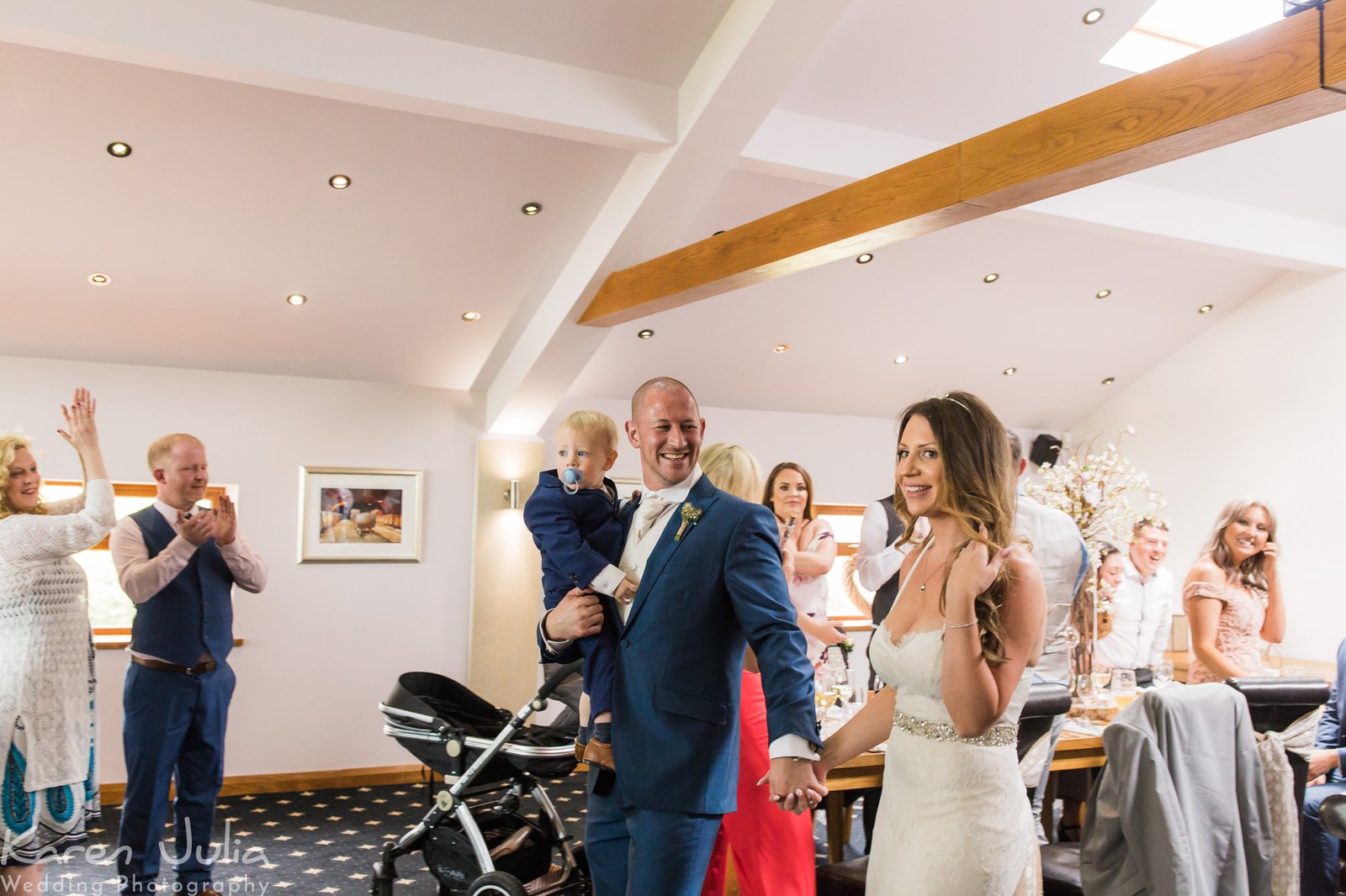 bride and groom enter wedding breakfast room, greeted by guests