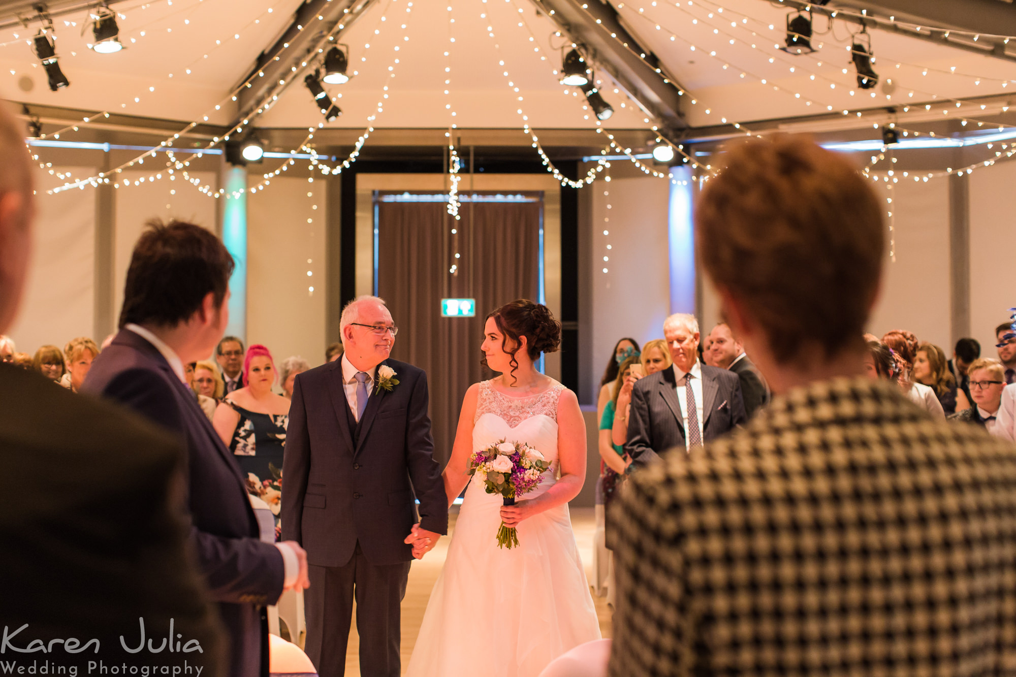 bride and dad walk down the aisle together at Lowry Theatre wedding ceremony