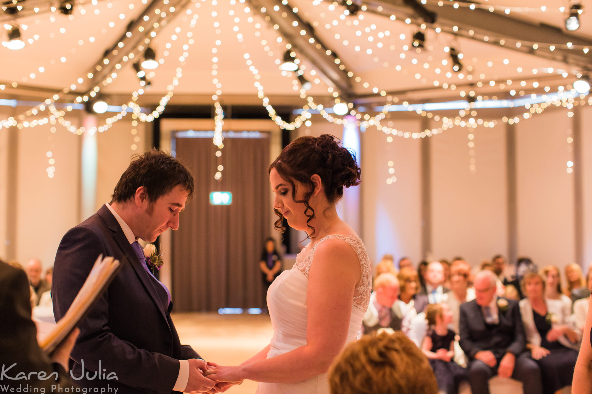 bride and groom exchange rings during their Lowry Theatre wedding ceremony