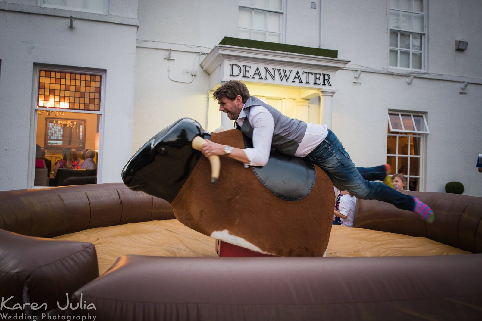 groom grips on to rodeo bull and summer wedding reception