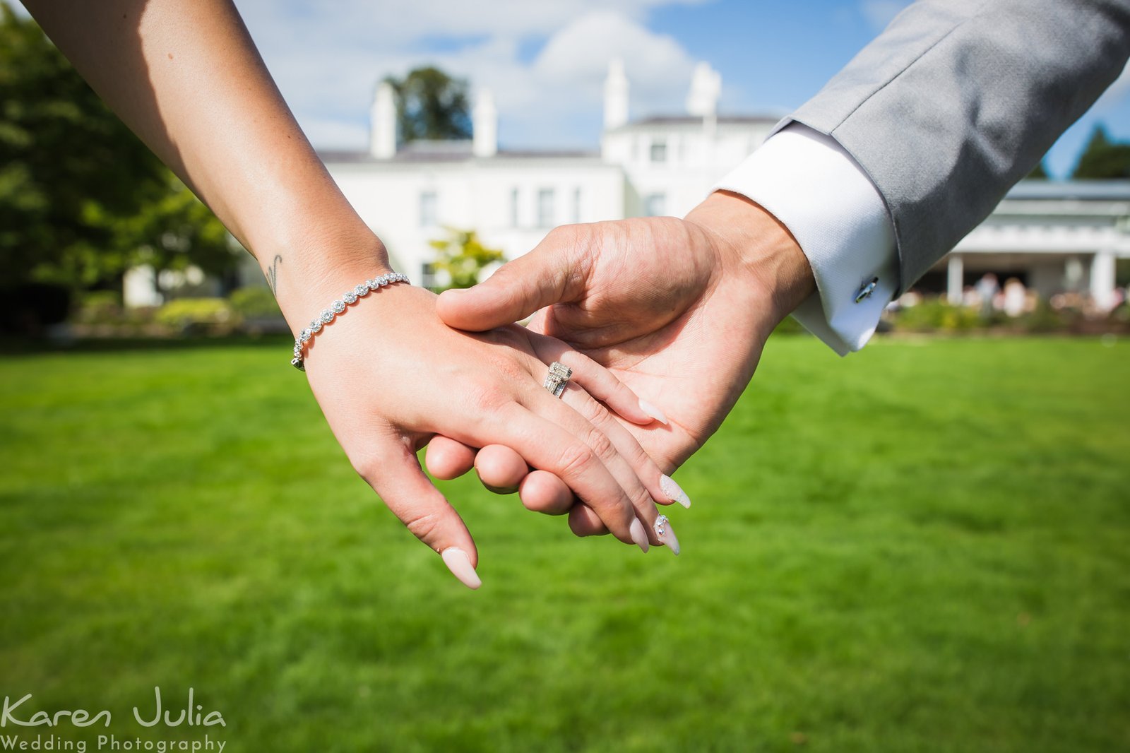 bride and groom detail shot of hands with the wedding venue Chancellors Hotel in the background