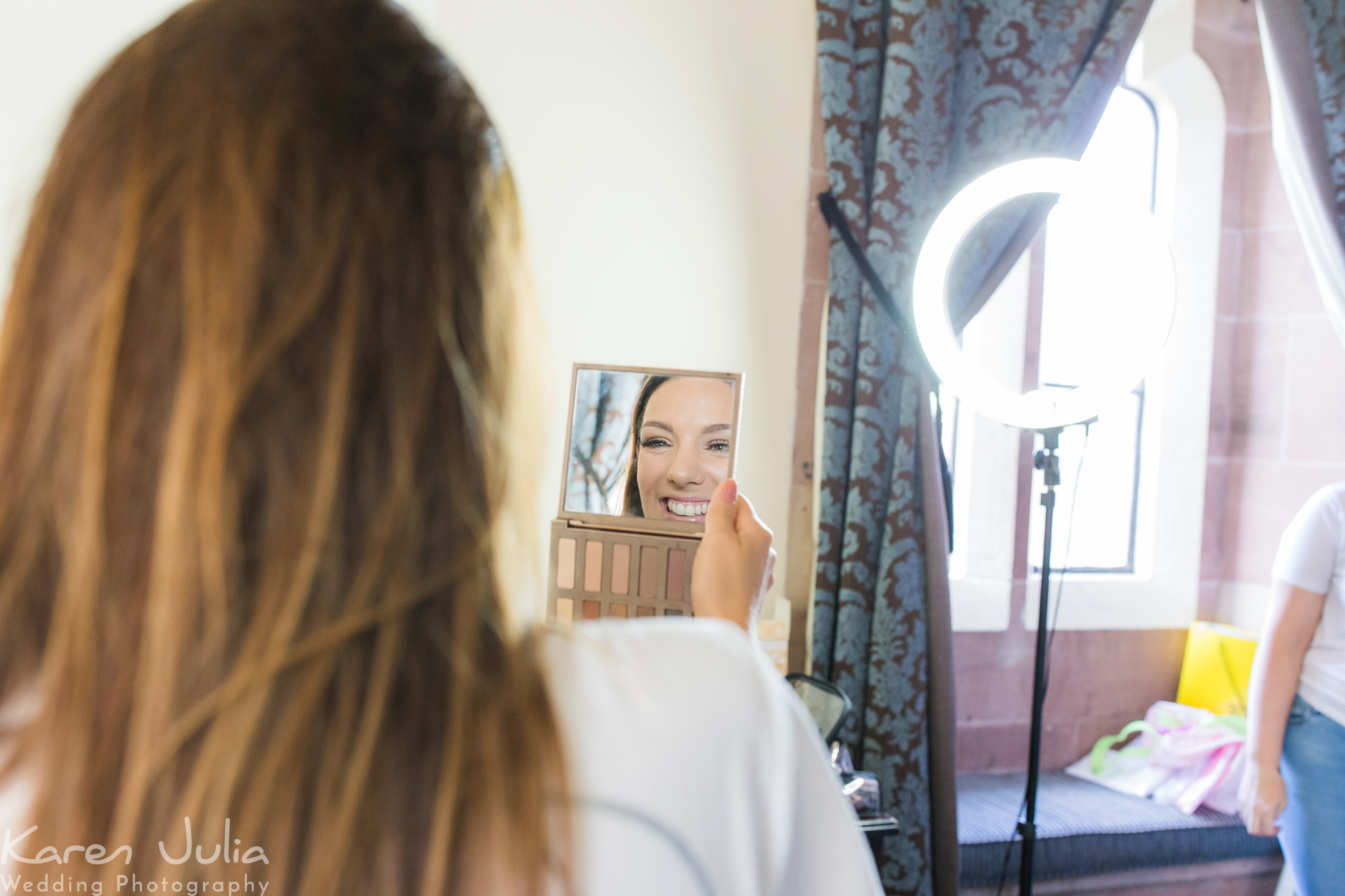 bride checks her make-up in the mirror at Peckforton Castle
