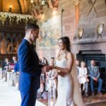 bride and groom exchange rings during wedding ceremony at Peckforton Castle