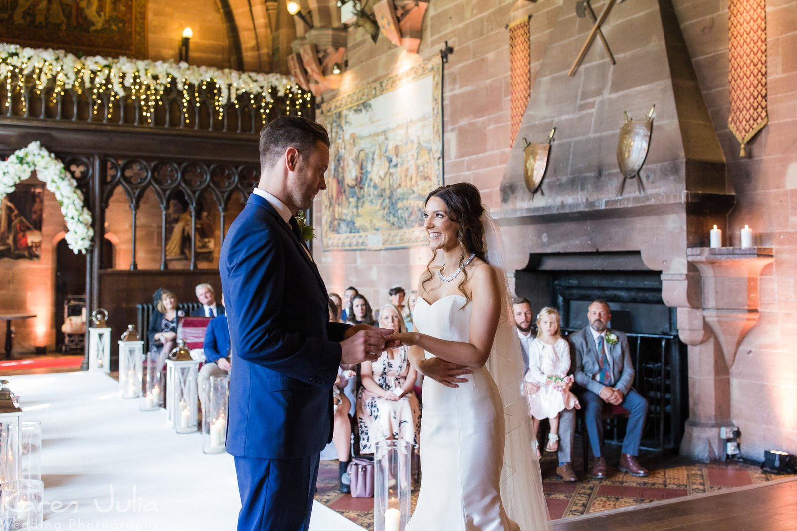 bride and groom exchange rings during wedding ceremony at Peckforton Castle