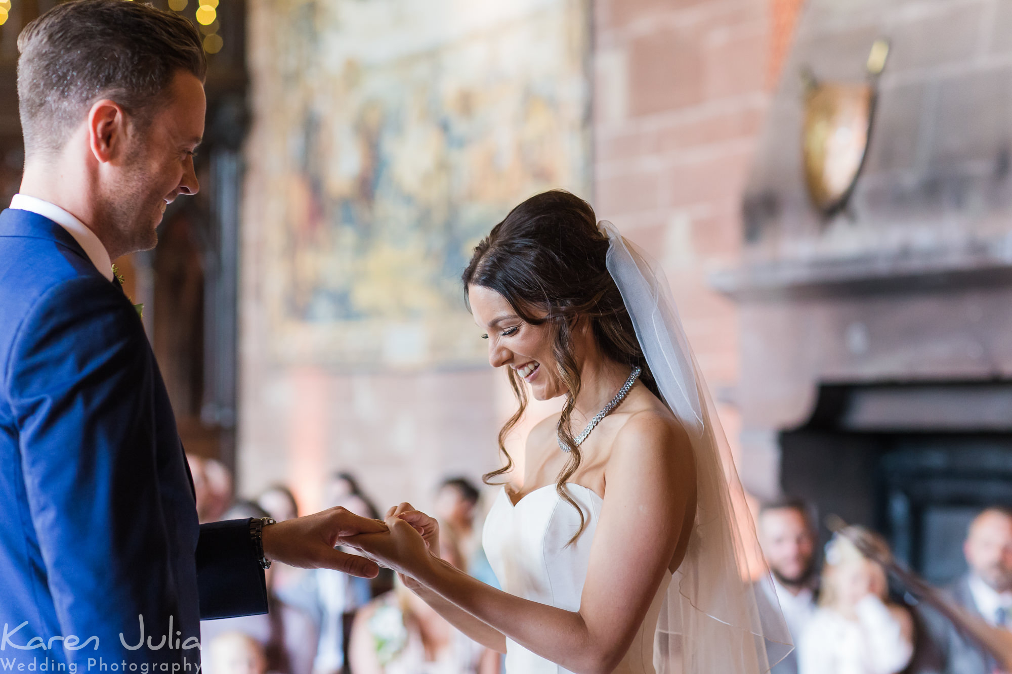 bride and groom exchange rings during Peckforton Castle wedding ceremony