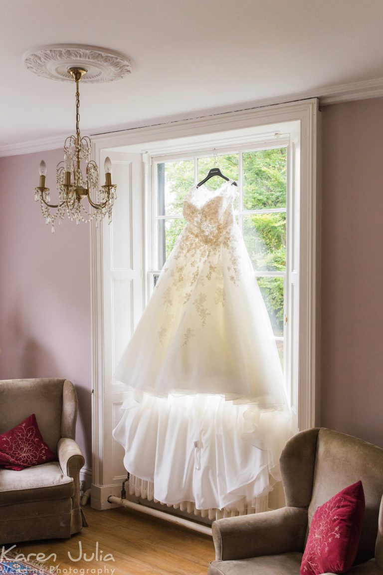 wedding dress hanging in front of windo at Statham Lodge