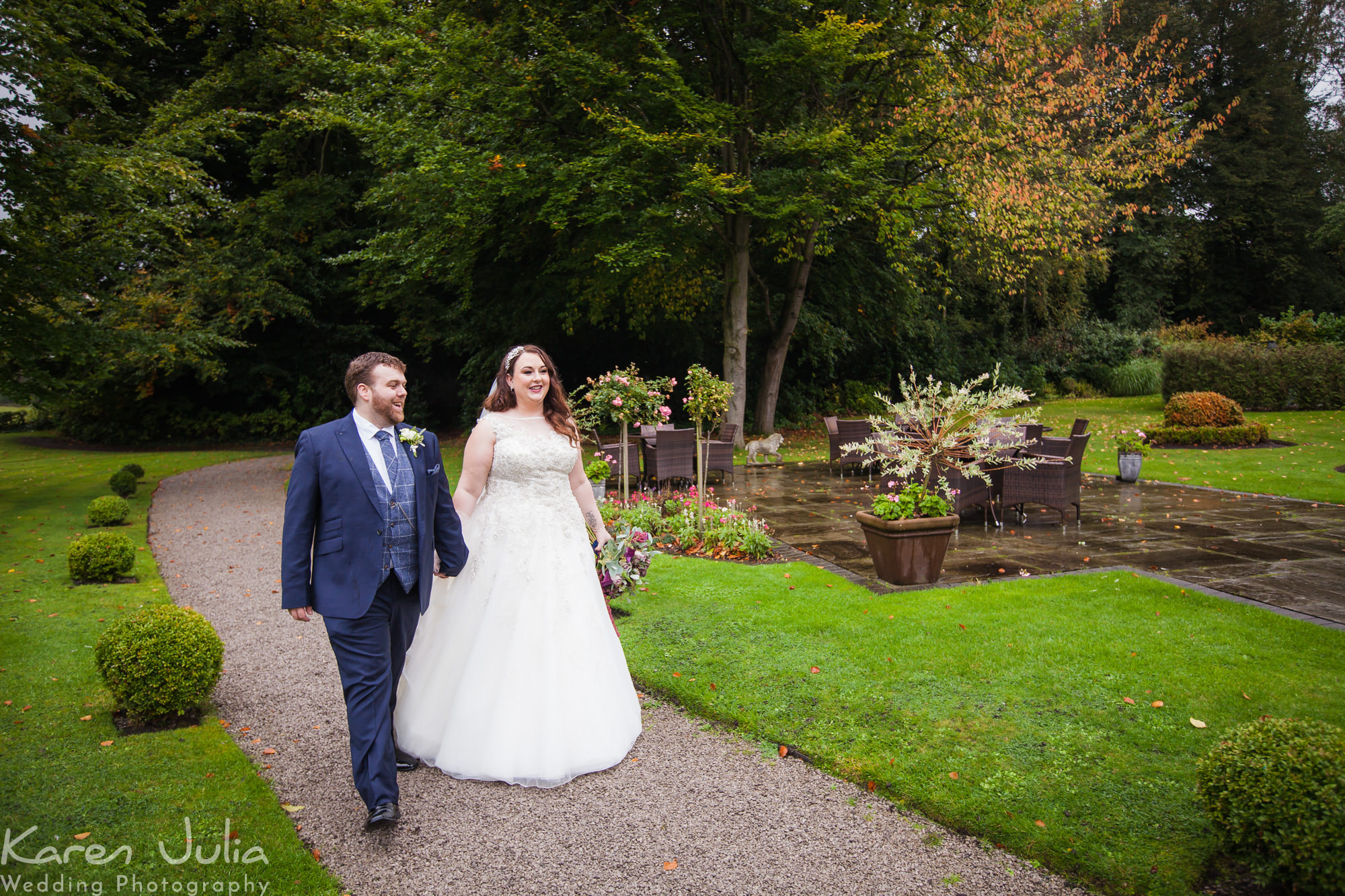 bride and groom walk through the gardens at statham Lodge hotel
