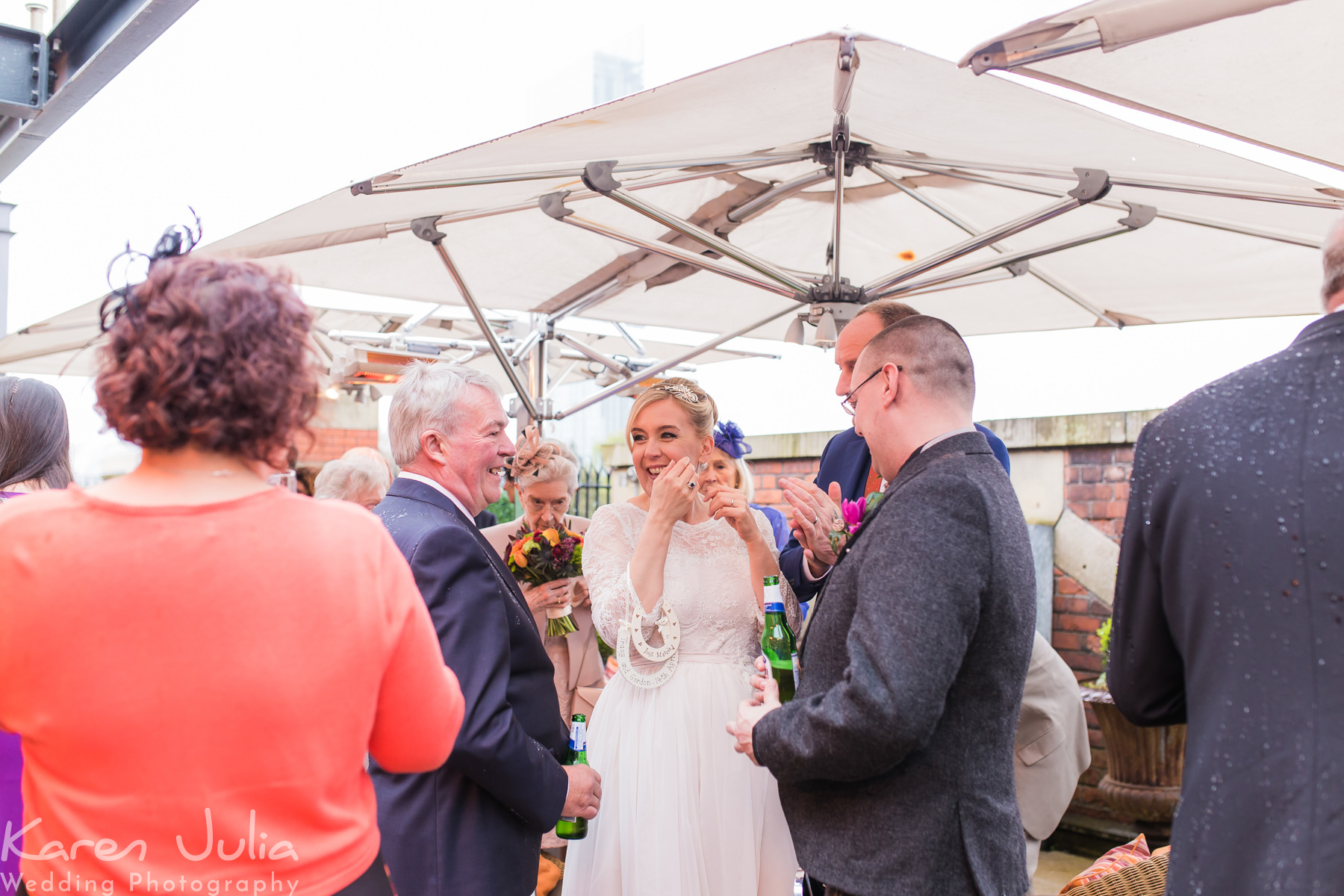 bride and groom chat with guests under the umbrellas on the roof terrace