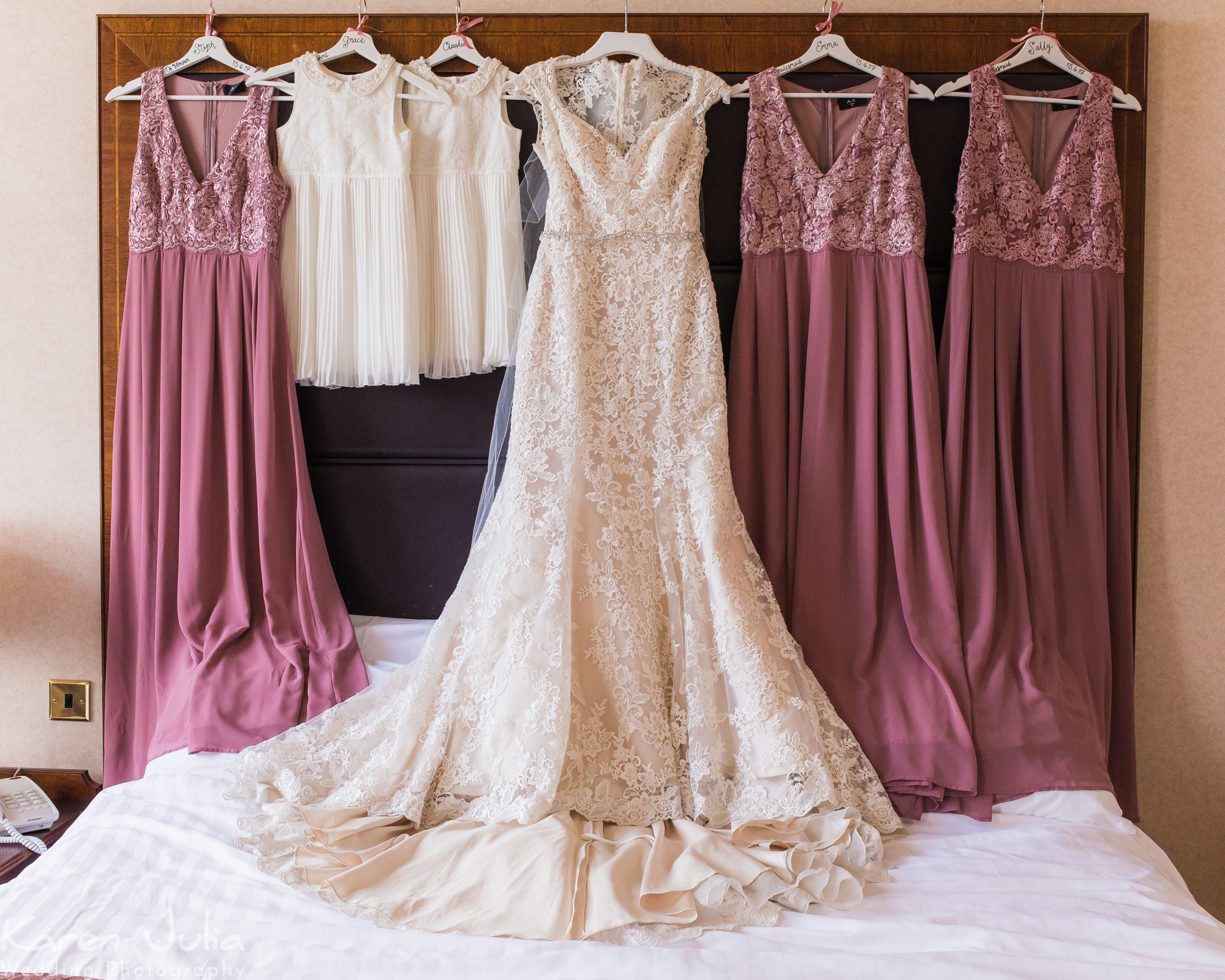 wedding and bridesmaids dresses hanging above bed in Shrigley Hall