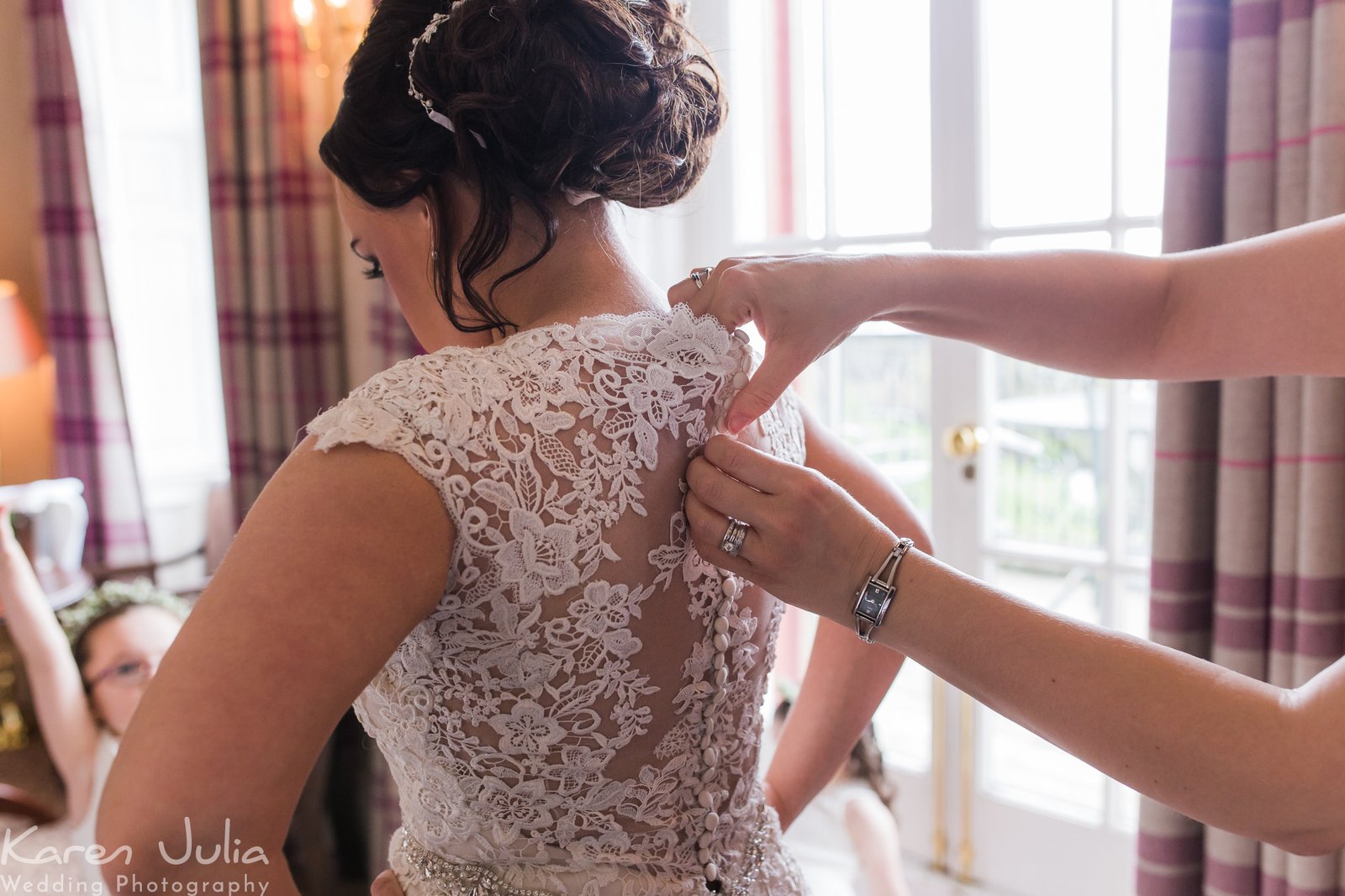 brides dress is fastened at Shrigley Hall before the edding ceremony