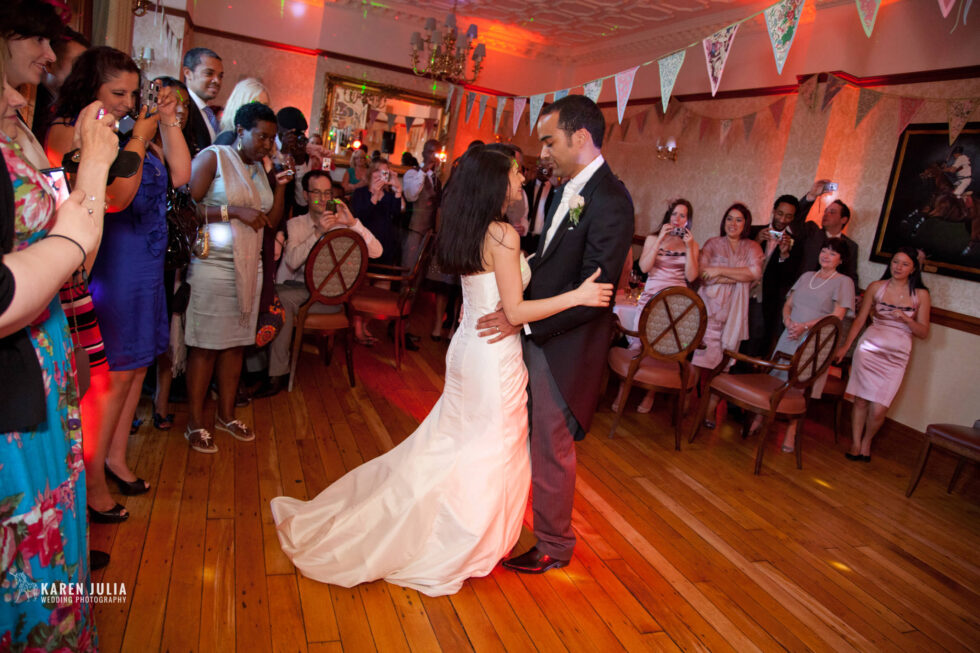 bride and groom have their first dance together as guests watch on