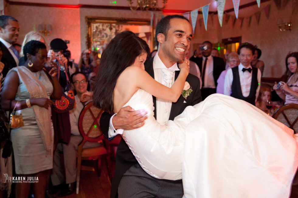 groom holds his bride on the dance floor after their first dance together at their wedding reception