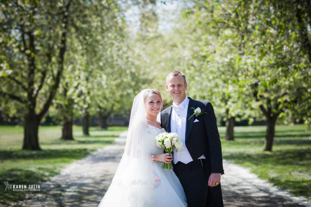 bride and groom pose for a portrait in the tree lined entrance of Victorian stately home Thoresby Hall
