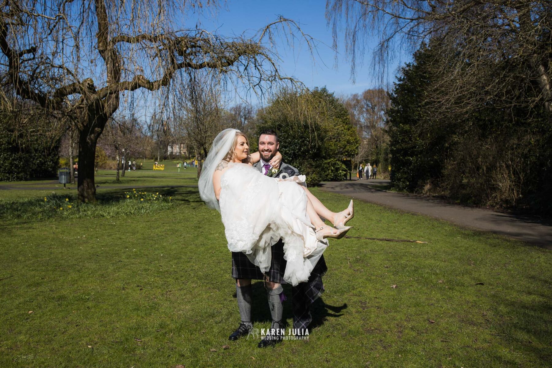 groom carries bride to the grass area for couple portraits in Maxwell Park