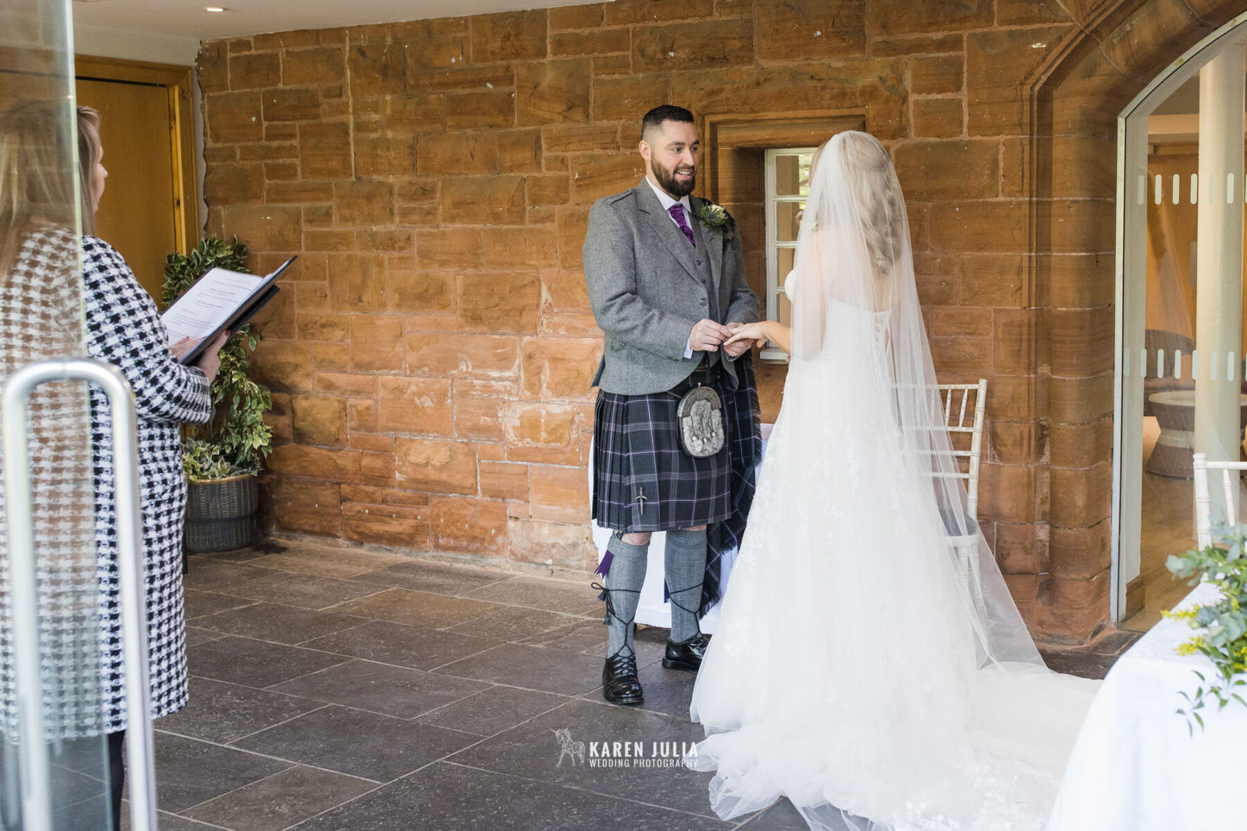 groom places ring on brides finger during their Pollokshields Burgh Hall Wedding Photos