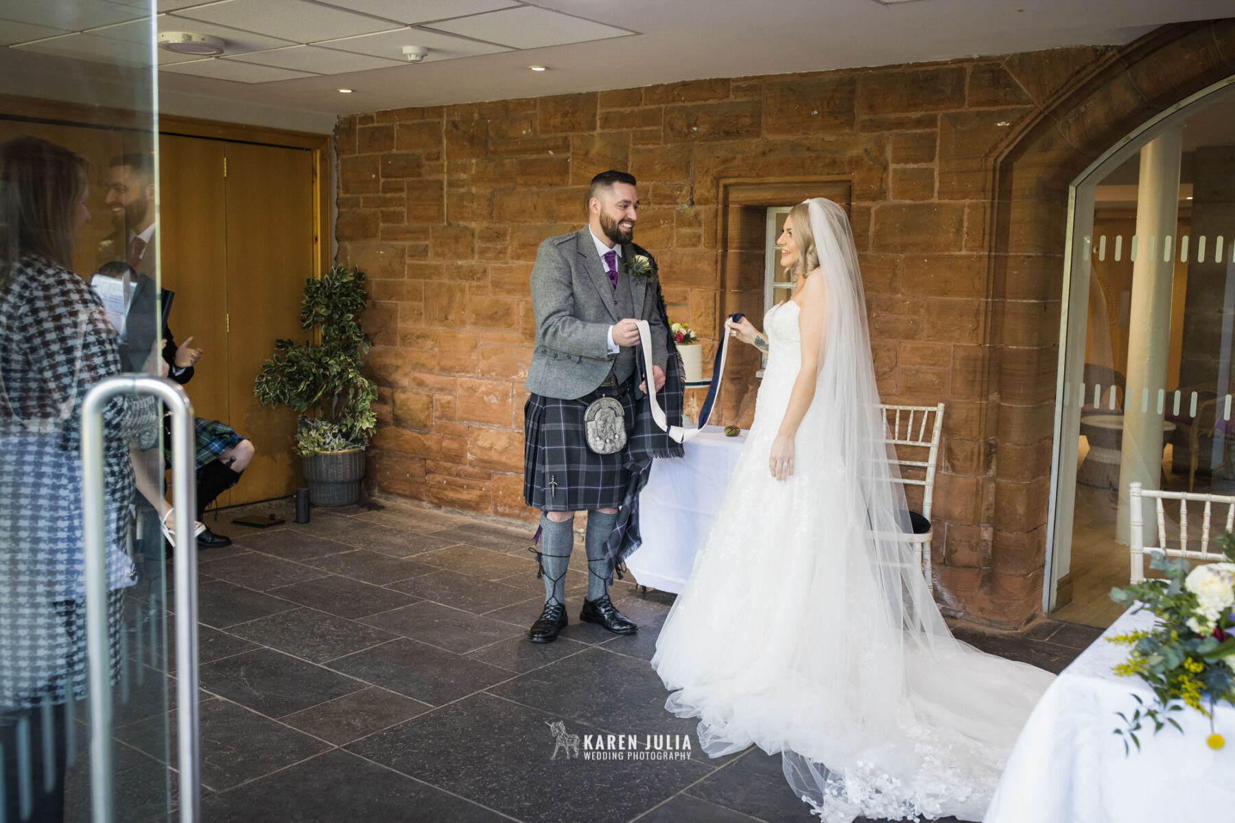 bride and groom tie the knot with ribbon at their Pollokshields Burgh Hall Wedding 
