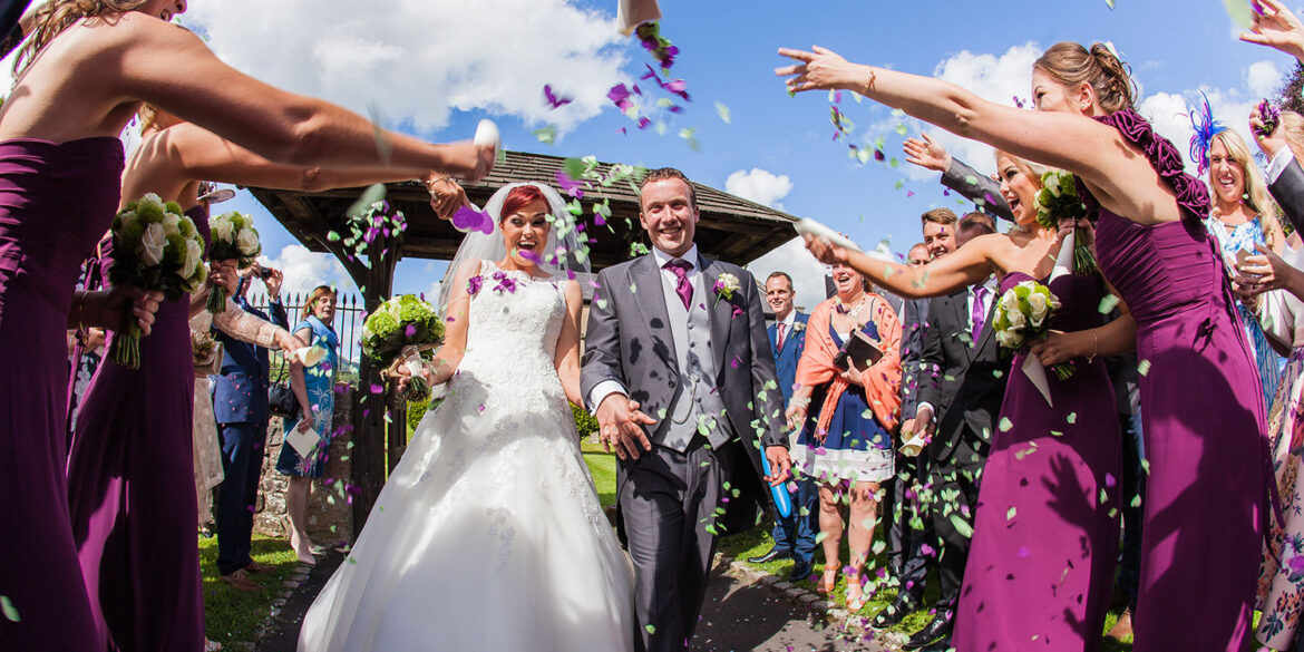 guests throw confetti at a sunny summer wedding