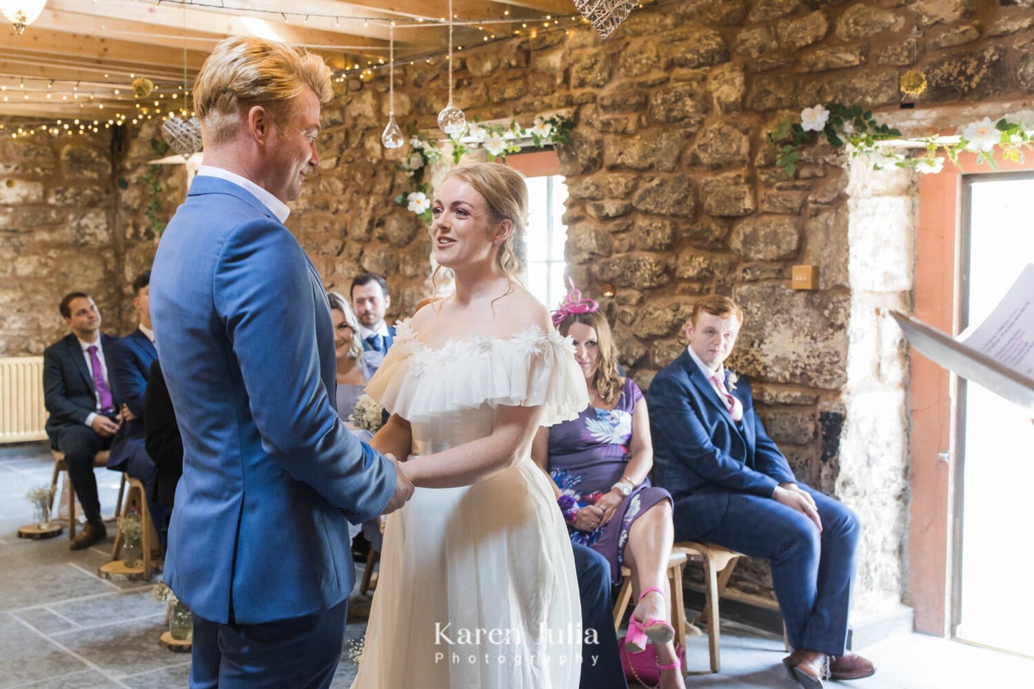 bride and groom face each other and hold hands during wedding ceremony