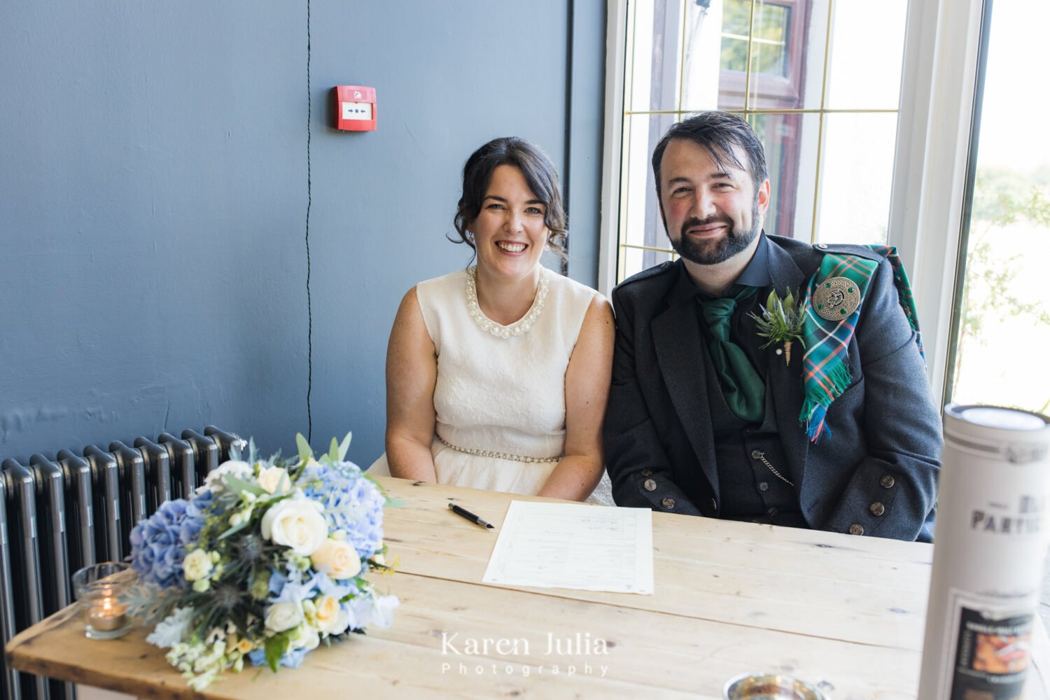 bride and groom pose for a photo with the wedding register in the farmhouse