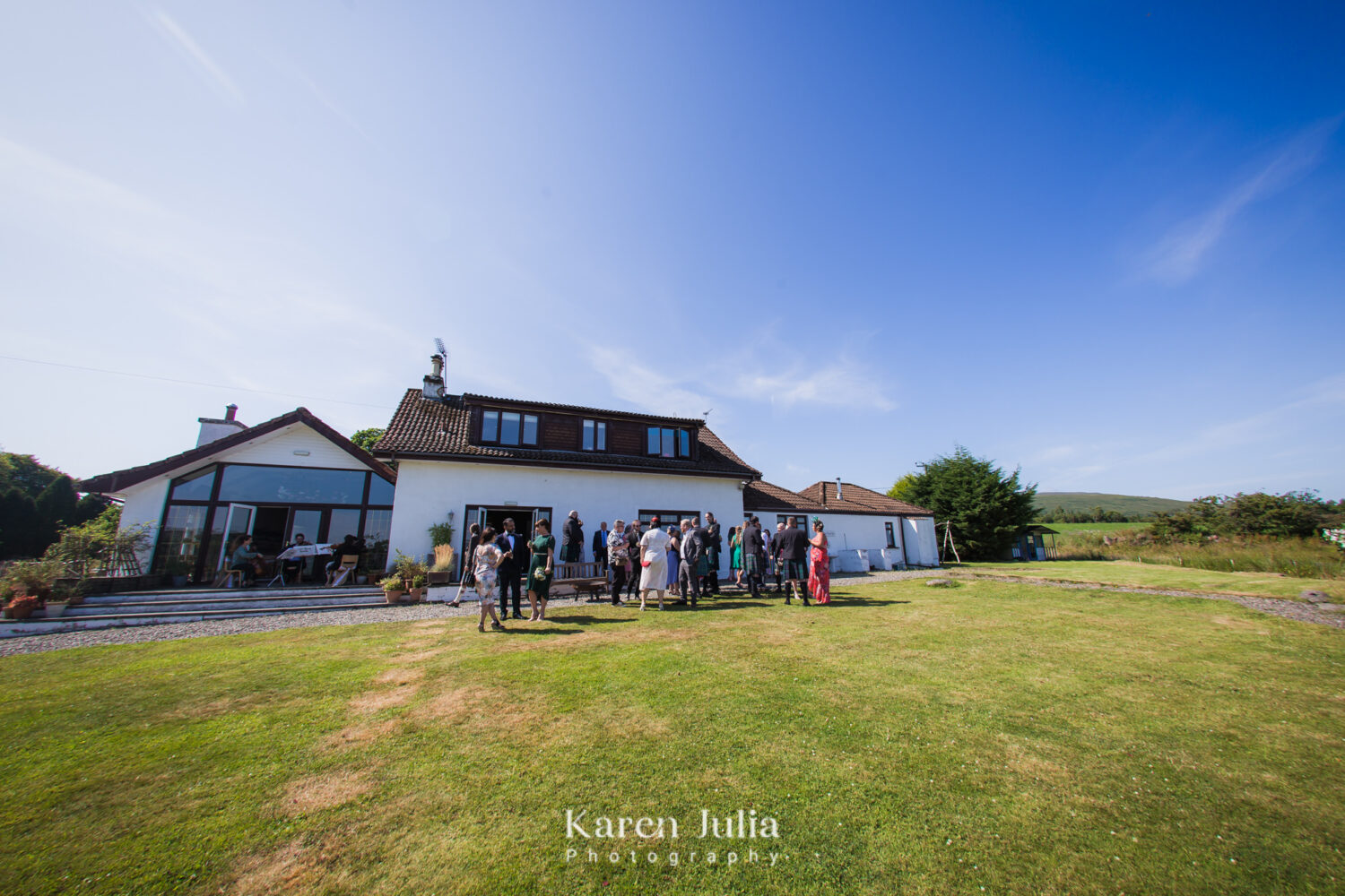 exterior photo of the farmhouse at Fruin Farm with guests mingling on the grass area