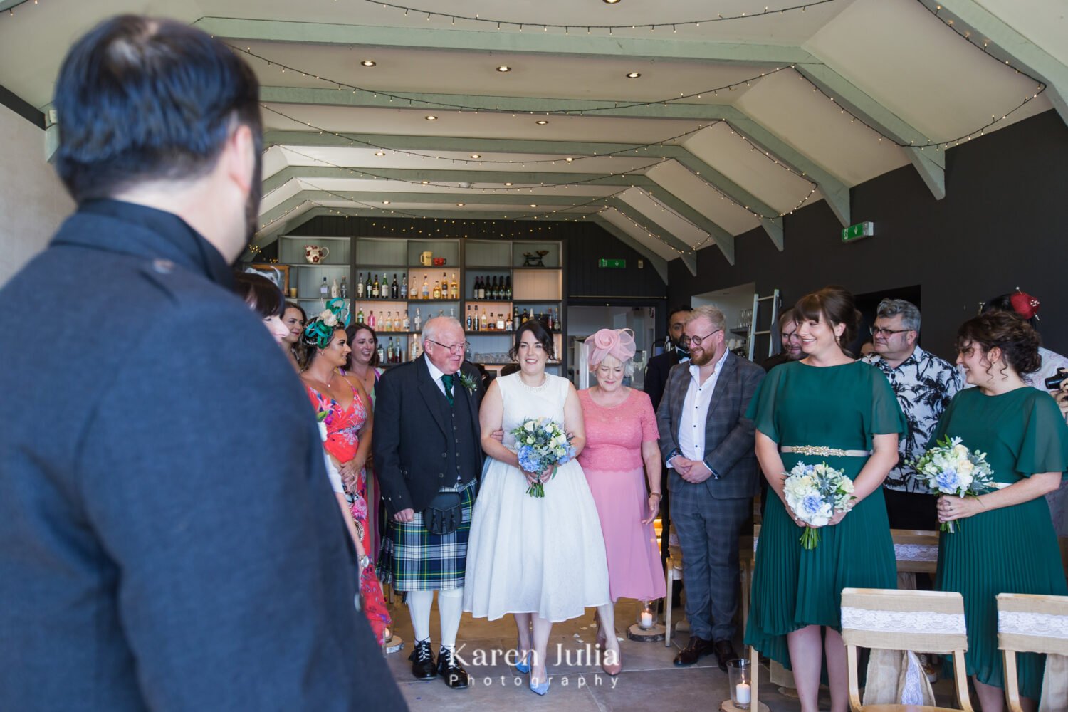 bride walks down the aisle in the farmhouse at Fruin Farm with her parents accompanying her