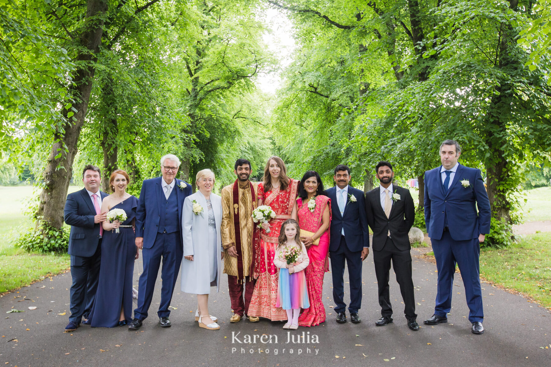a group photo of the wedding party in traditional Indian dress in Bellahouston Park