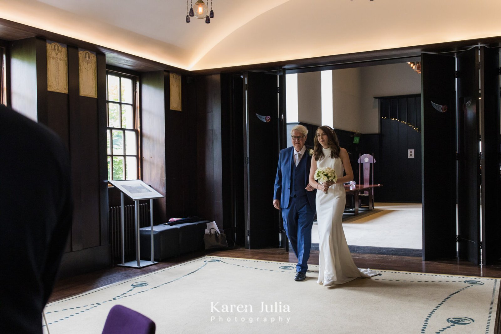 bride walks into wedding ceremony room arm in arm with her Dad