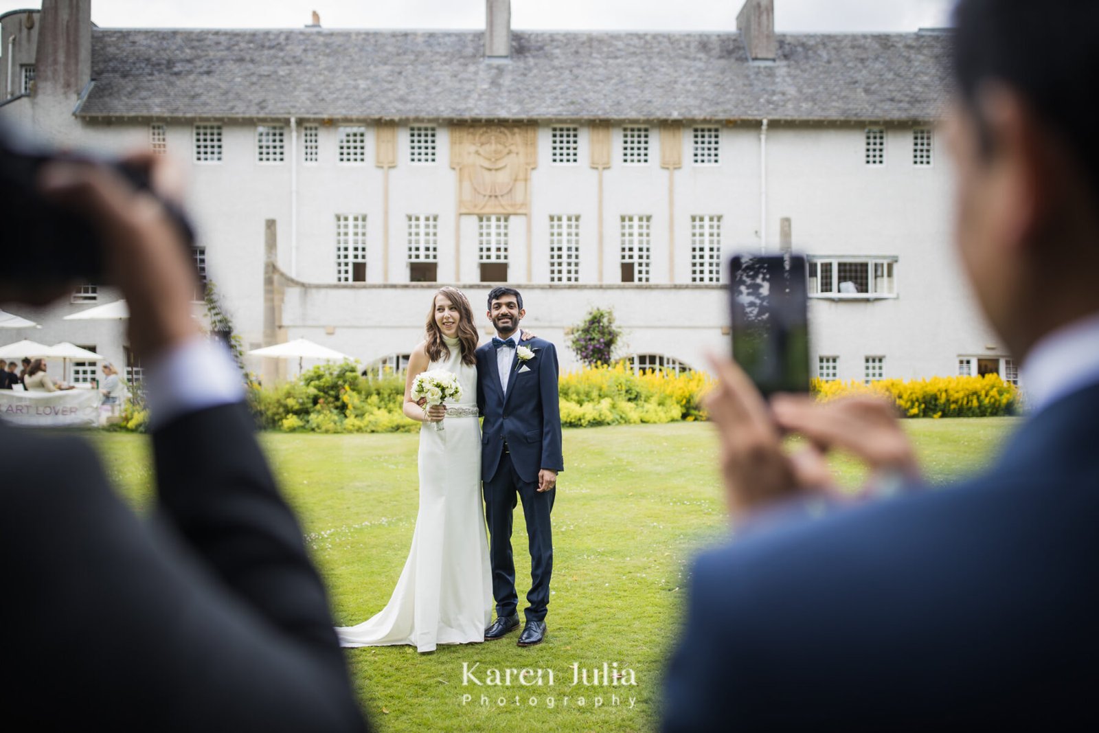 bride and groom pose for photos for their guests, in front of House for an Art Lover